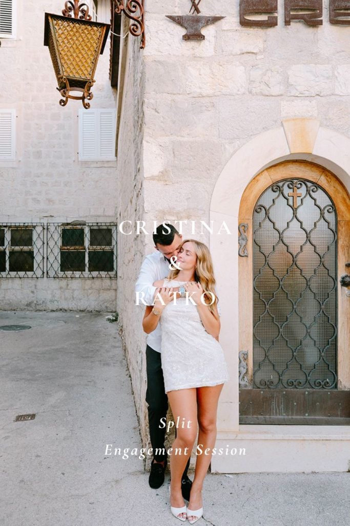 Zaručnik ljubi zaručnicu u obraz stojeći ispred kamenog zida u uskoj ulici tijekom zaručničkog fotografiranja u Splitu.
