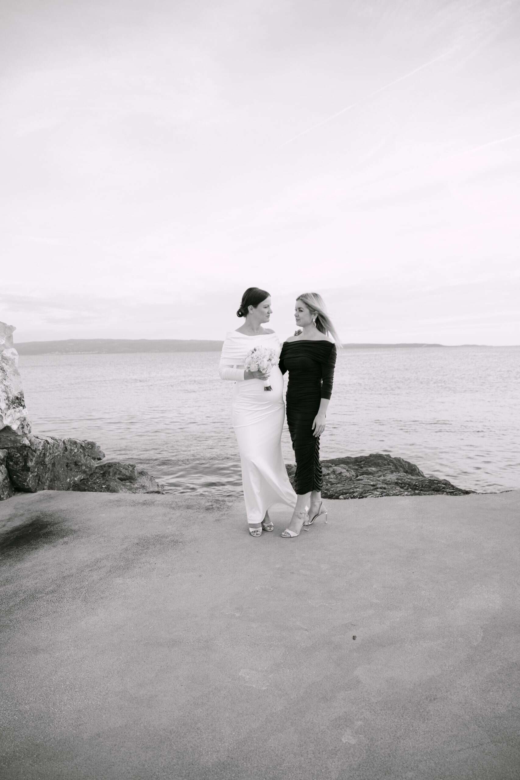 Kuma i mladenka Antonija stoje na plaži, okrenute jedna prema drugoj, s morem u pozadini.