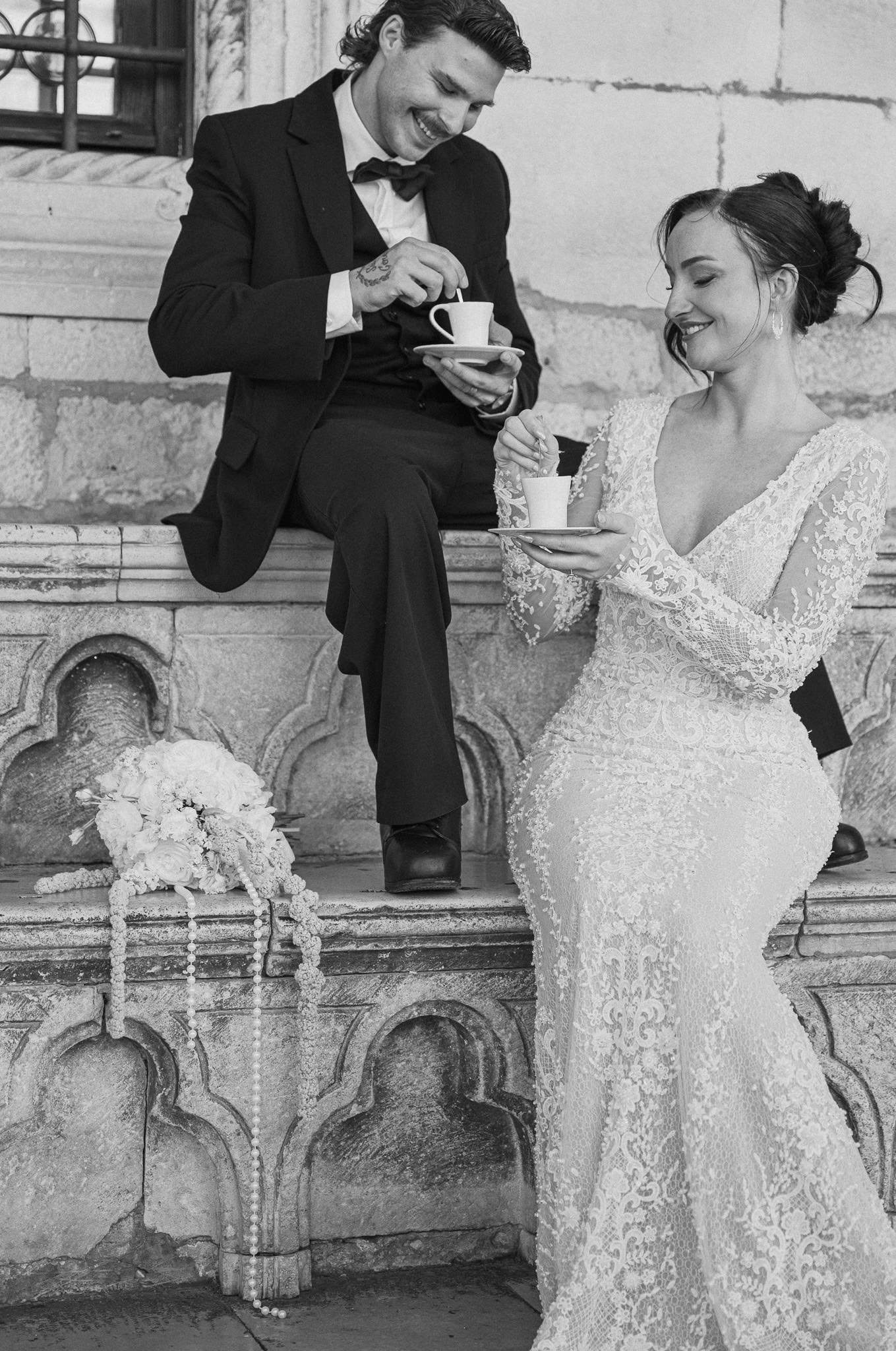 Stari grad Dubrovnik – opušteni crno-bijeli portret; nasmiješeni mladenci uživaju u kavi sjedeći na povijesnoj kamenoj klupi s ukrasima.