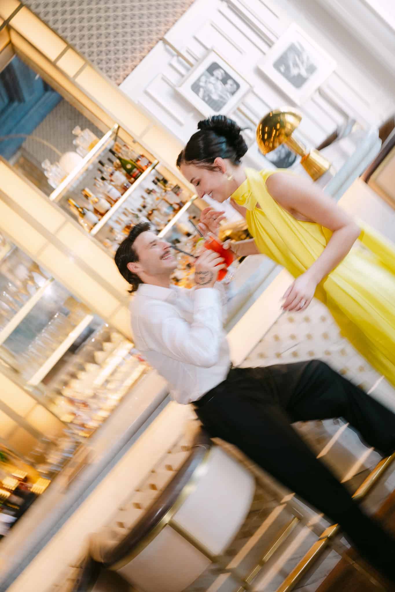 Dubrovnik, luksuzni bar - dinamičan vjenčani portret; mladenka u modernoj žutoj haljini i mladoženja nazdravljaju pićem uz osmijeh.