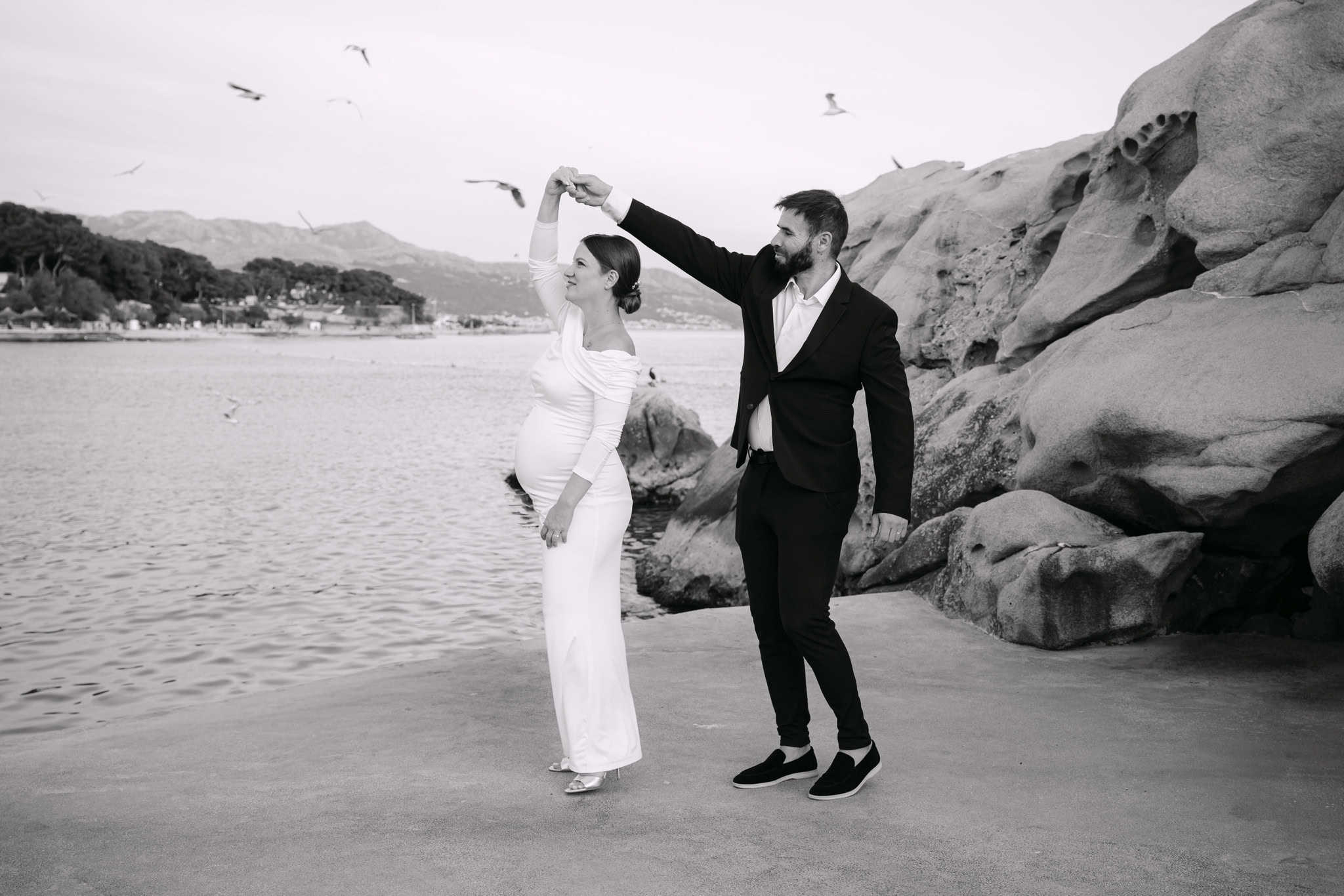 Romantična fotografija vjenčanog para na plaži, ples uz more i galebove, crno-bijela fotografija.