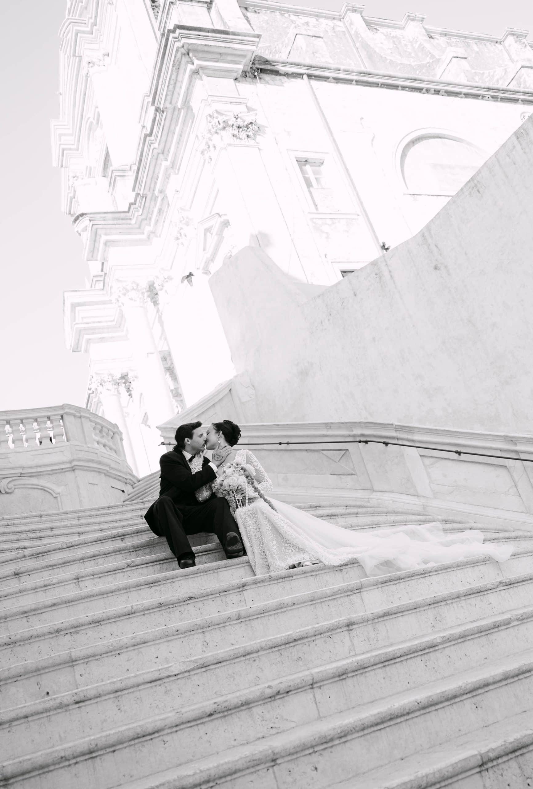 Vjenčanje u Dubrovniku, par na vrhu baroknih skala; vjenčanica koja se prostire niz kamene stepenice.