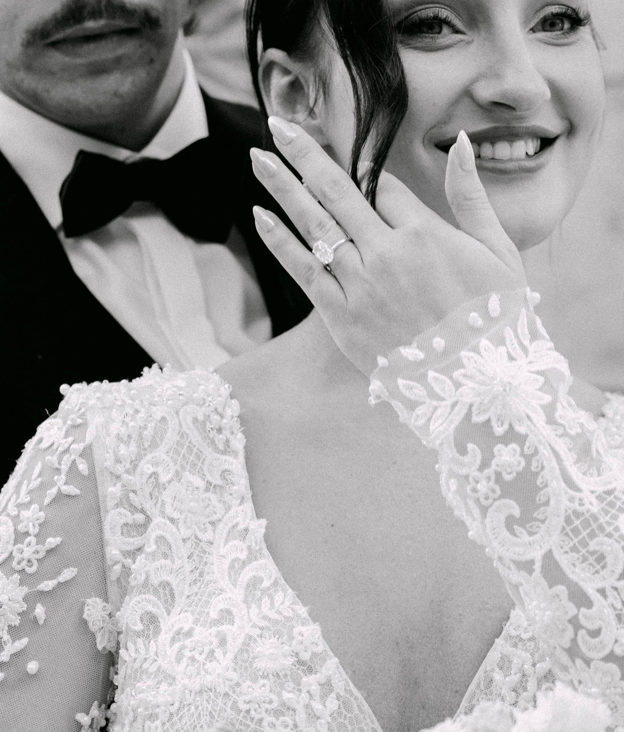 Dubrovnik vjenčanje – spontani crno-bijeli portret nasmiješene mladenke; krupni plan ruke s prstenom i bogatih čipkastih detalja na vjenčanici uz mladoženju u pozadini