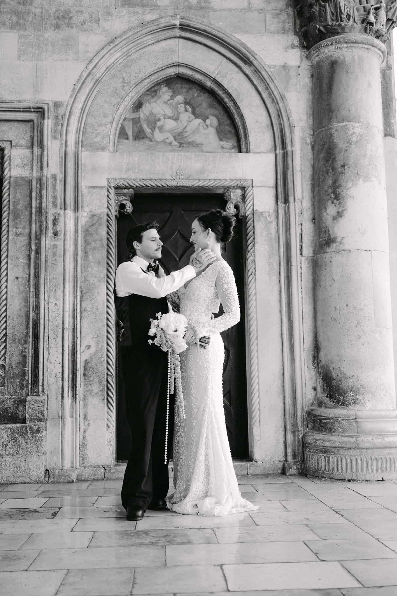 Dubrovnik wedding session - mladenci poziraju ispred monumentalnih kamenih vrata unutar zidina Starog grada.