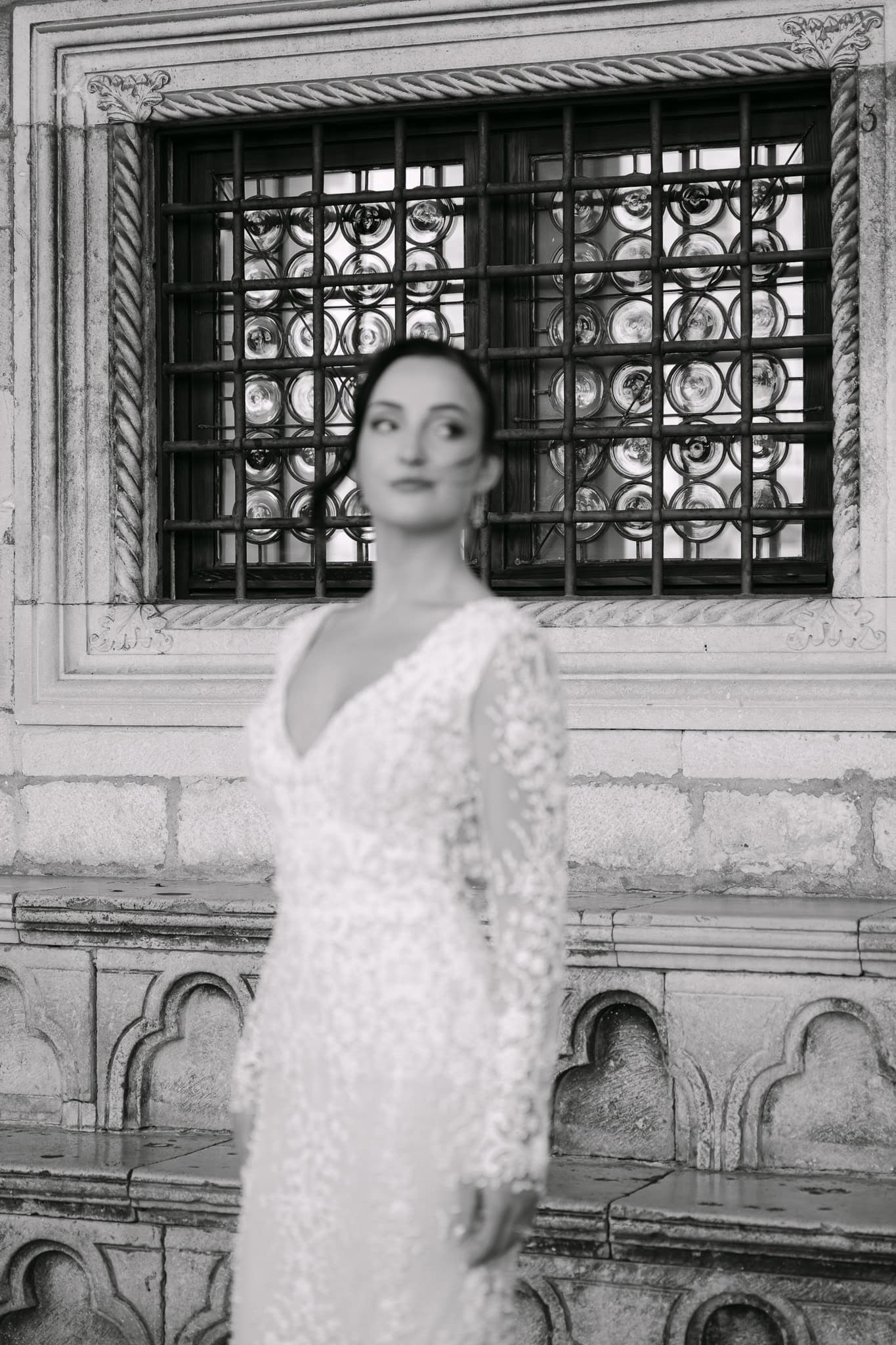 Dubrovnik, povijesna jezgra – crno-bijeli portret mladenke; elegantna nevjesta stoji ispred starinskog prozora s detaljima od okruglog stakla i kovanog željeza.