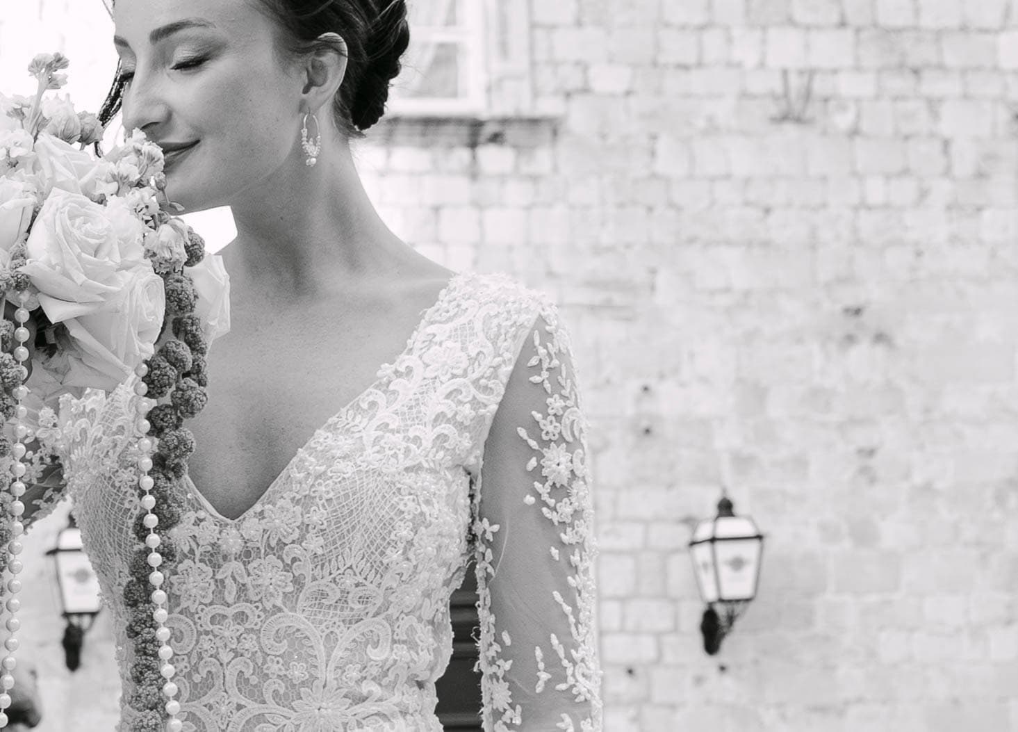 Dubrovnik wedding fotograf - nježan dokumentarni kadar nevjeste; crno-bijela fotografija mladenke u čipki uz teksturu starog dubrovačkog kamena.