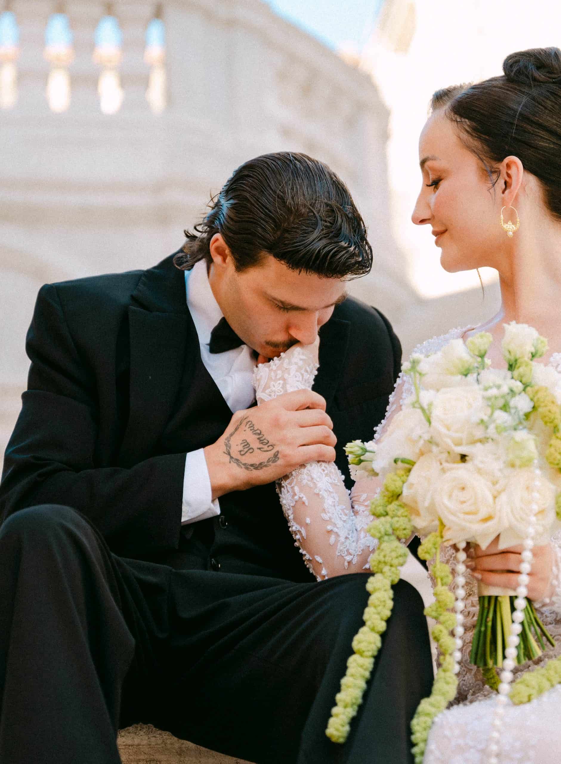 Dubrovnik, Stari grad - vjenčani portret na kamenim stepenicama; Orlando ljubi ruku Juliji koja drži bijeli buket ispred barokne pozadine.