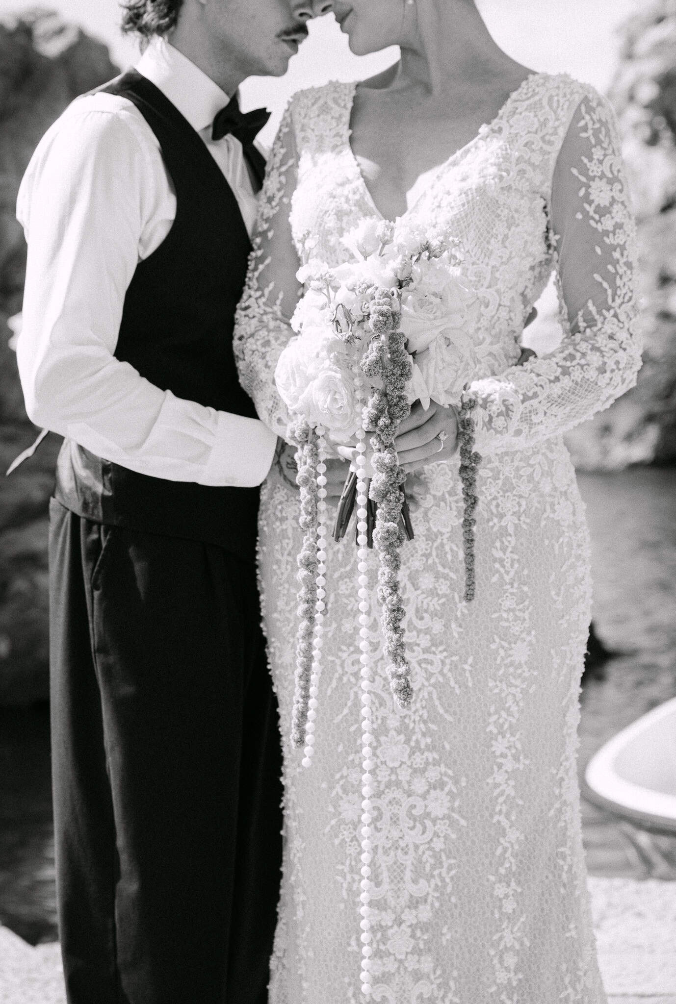 Vjenčanje u Dubrovniku - crno-bijeli detalj mladenaca; fokus na bogatu čipku vjenčanice i dugački bidermajer s biserima u nježnom dodiru.