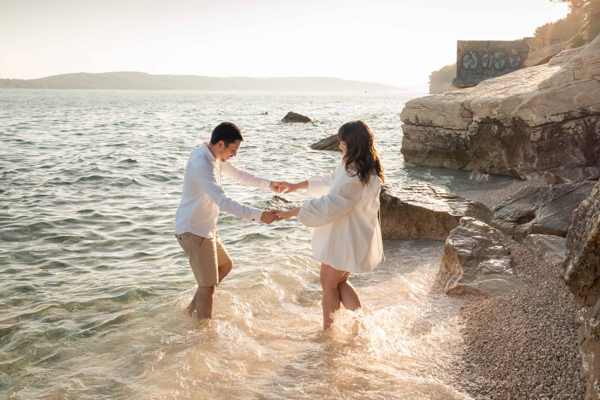 Par u bijelom bosi u moru; autentični trenuci zaruka uz zalazak sunca.