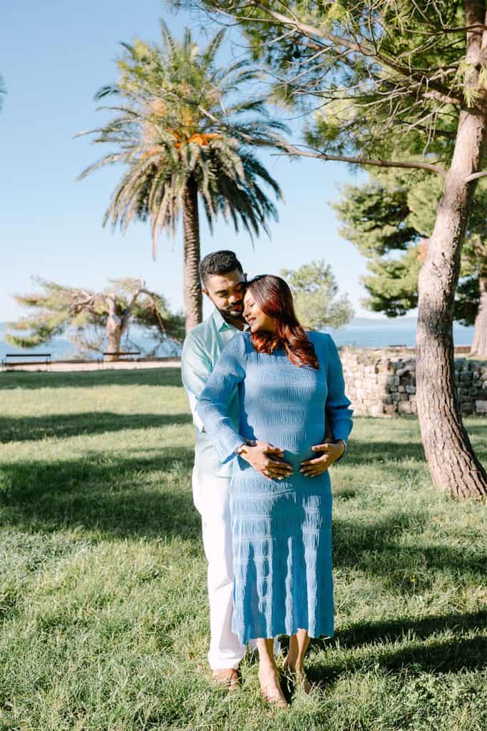 Trudni par na fotografiranju u prirodi, s palmama i zelenilom u pozadini, za uspomenu na posebno razdoblje.