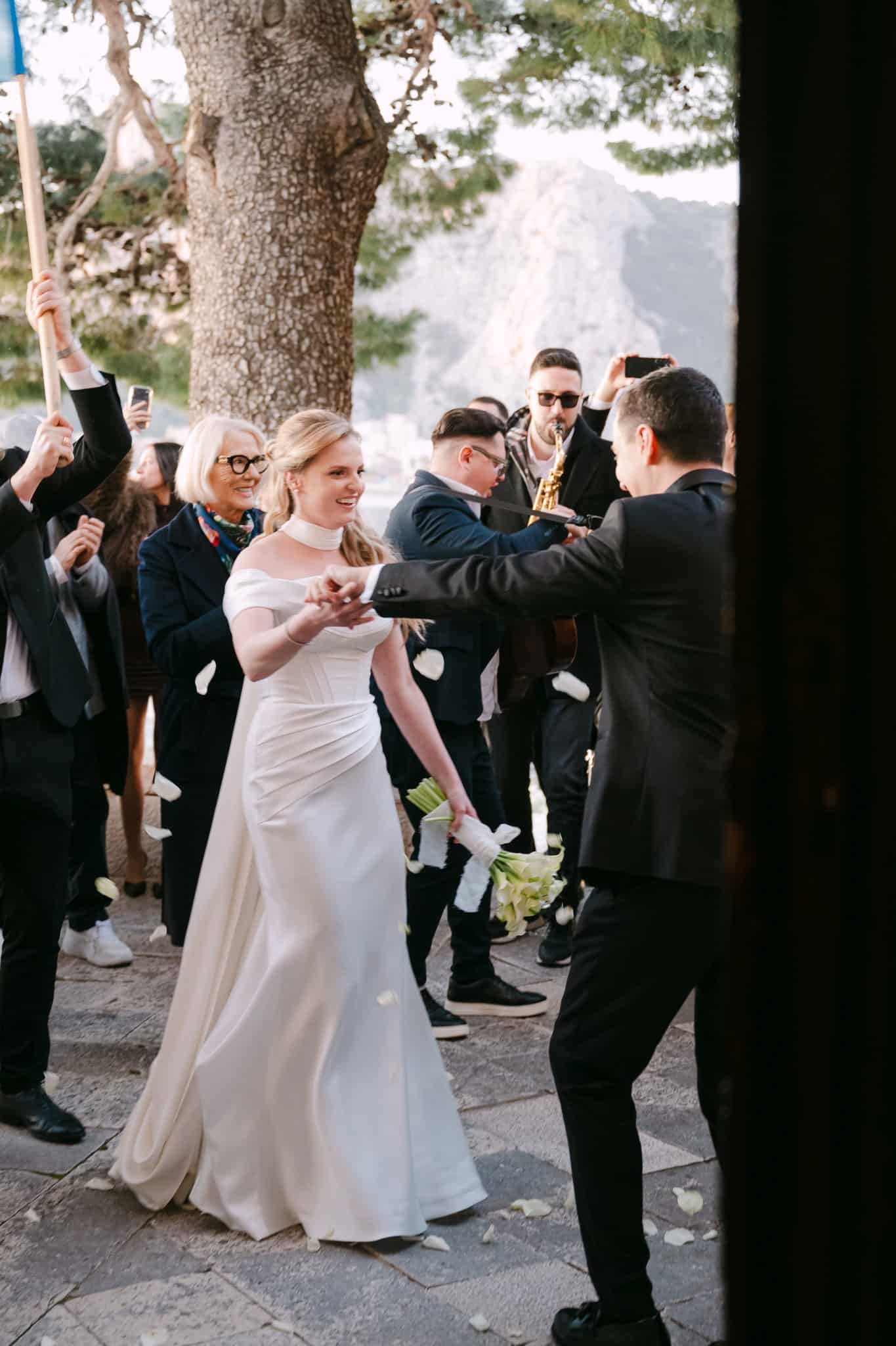 Mladenci plešu na otvorenom ispred crkve uz pratnju žive glazbe i benda sa saksofonom tijekom proslave vjenčanja u Omišu.