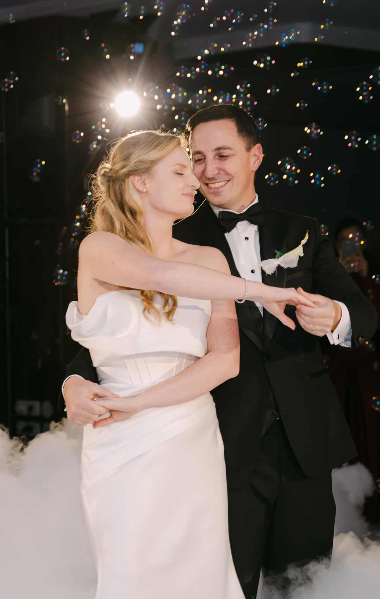 Prvi ples mladog para na svadbenoj zabavi, s efektima svjetlosti i mjehurićima u pozadini.