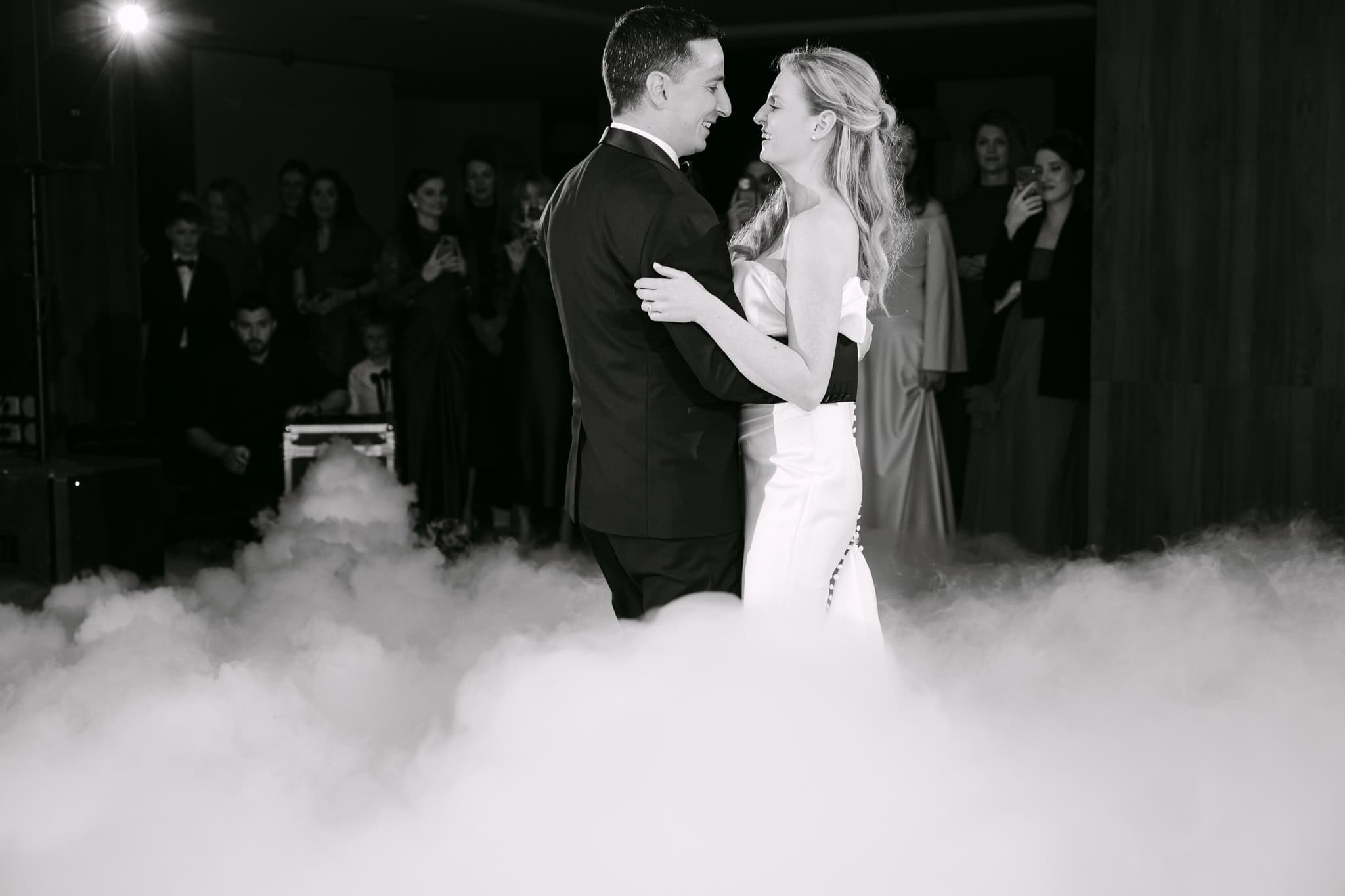 Vjenčani ples mladenaca na svadbenoj zabavi, romantična scena s dimom u pozadini.