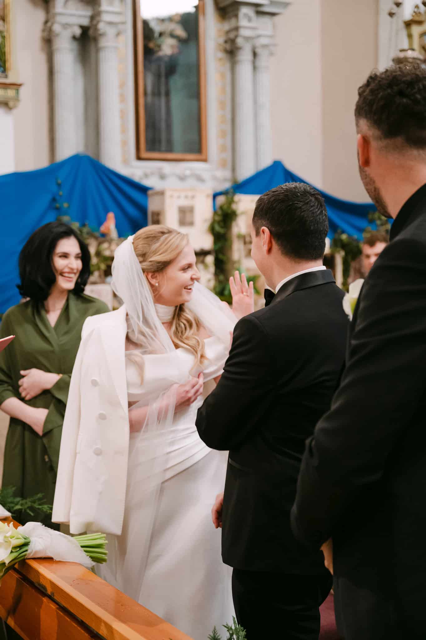 Nasmiješena mladenka okrenuta prema gostima i pokazuje svoj vjenčani prsten.