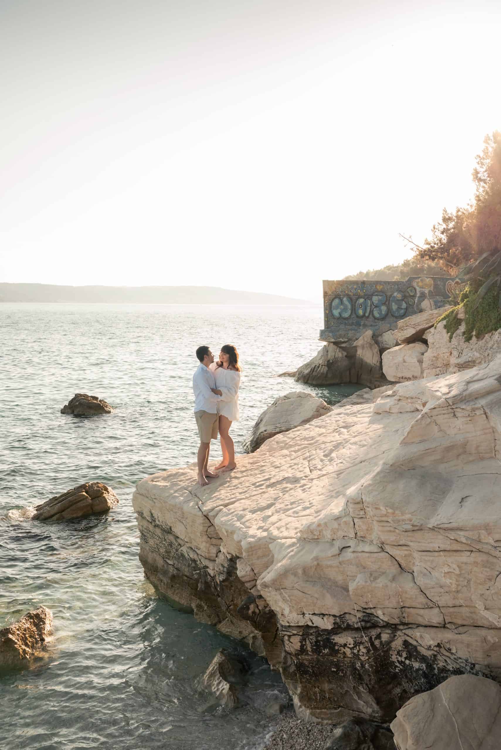 Split Obojena zaruke - Petra u bijeloj haljini i Ivan u bijeloj košulji u zagrljaju na stijenama