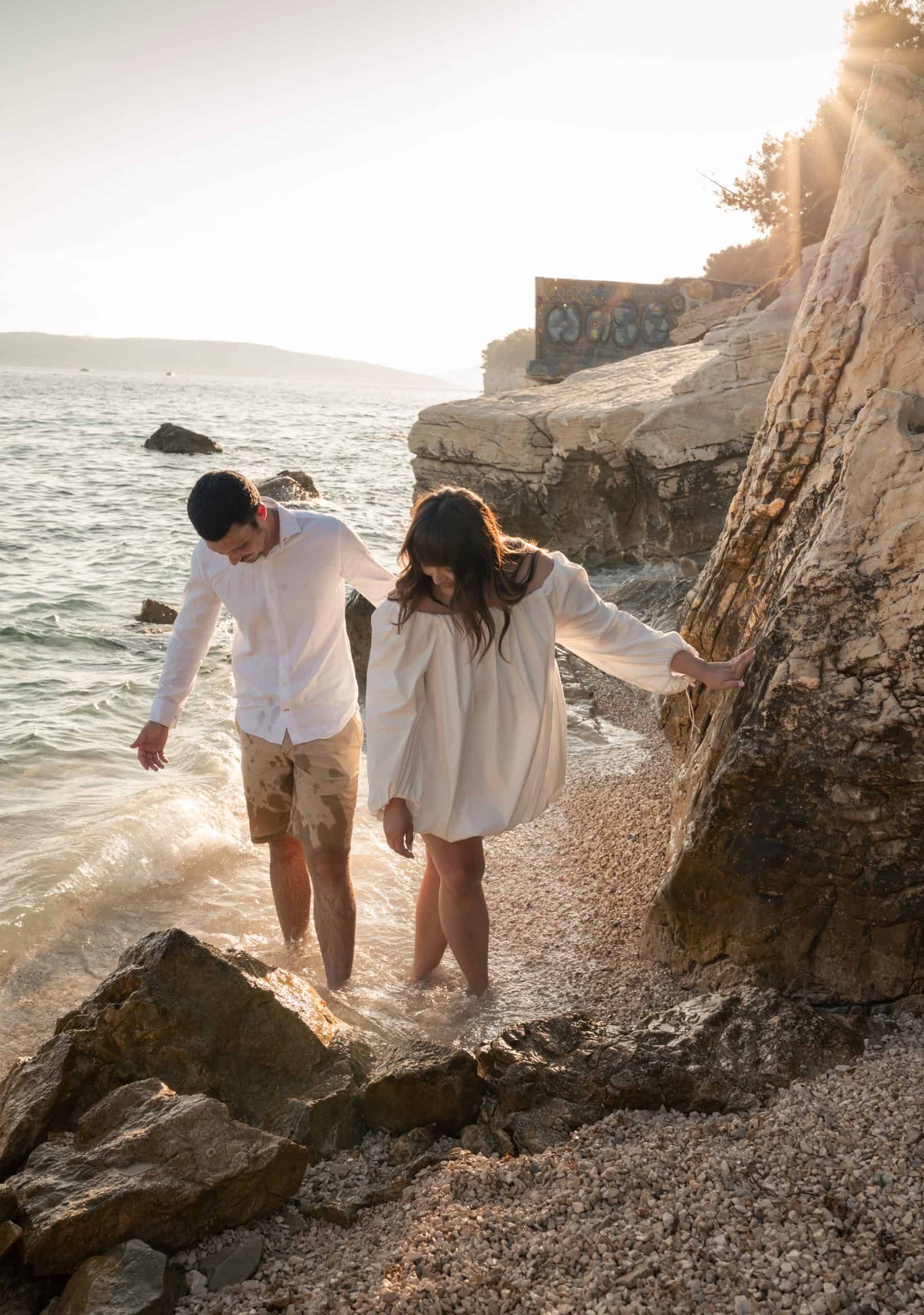 Zaručnici bosi u plićaku uvale Obojena tijekom zalaska sunca.