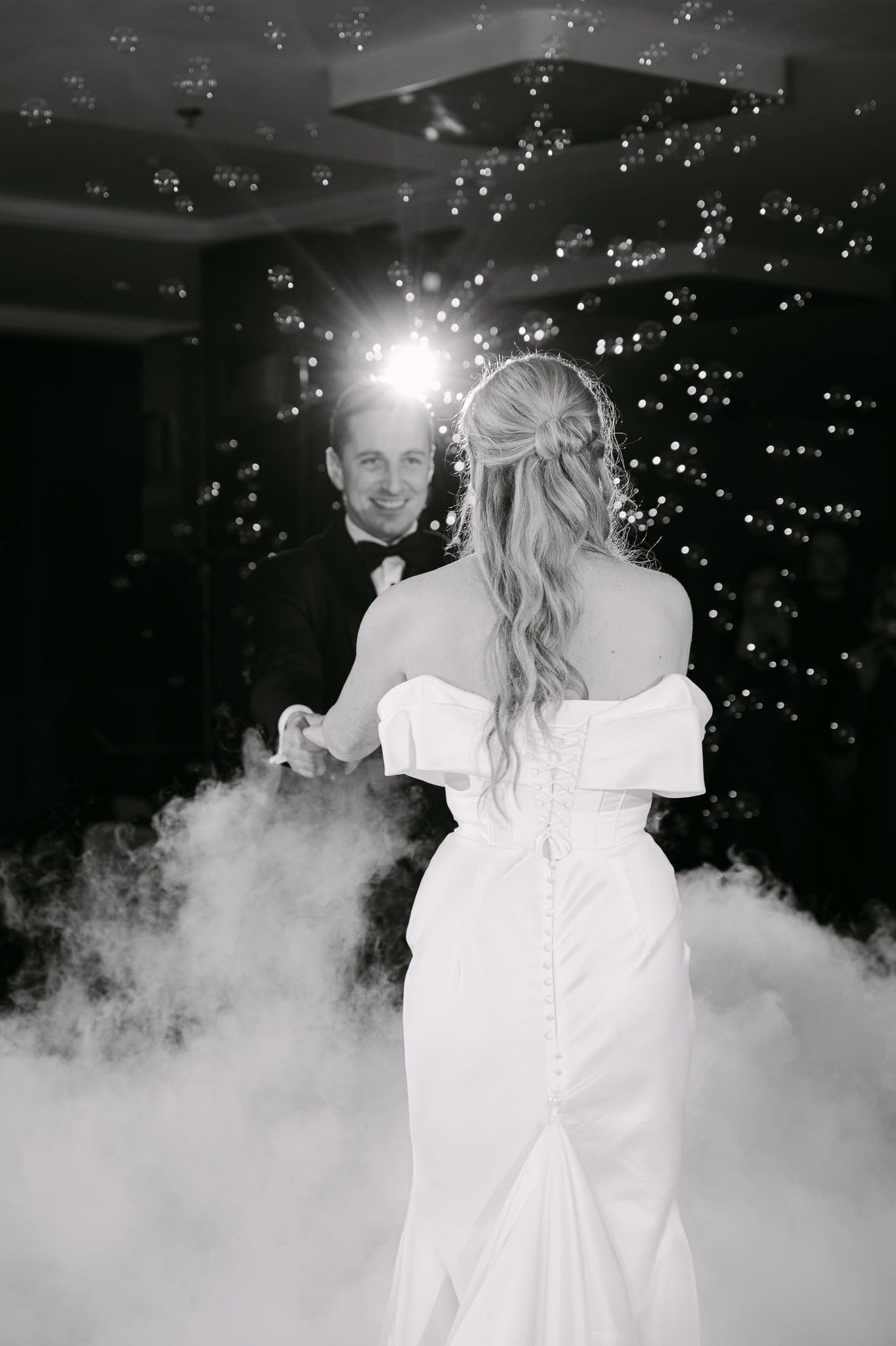 Vjenčani par na plesnom podiju, romantična fotografija s efektom magle i svjetlucavih svjetala u pozadini.