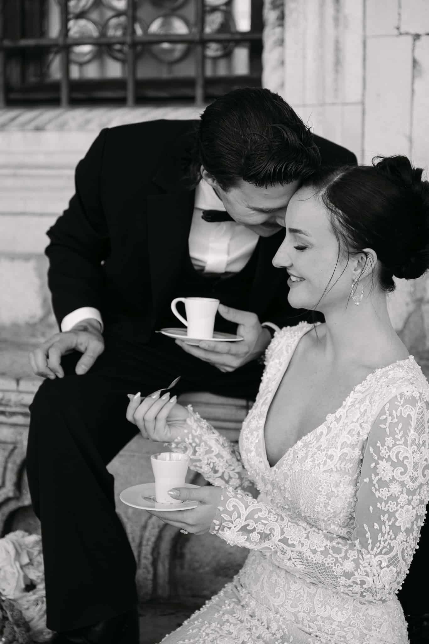 Dubrovnik vjenčanje – intimni crno-bijeli trenutak; mladoženja i mladenka sjede na kamenoj klupi ispred povijesnih prozora i nazdravljaju šalicama kave uz osmijeh.