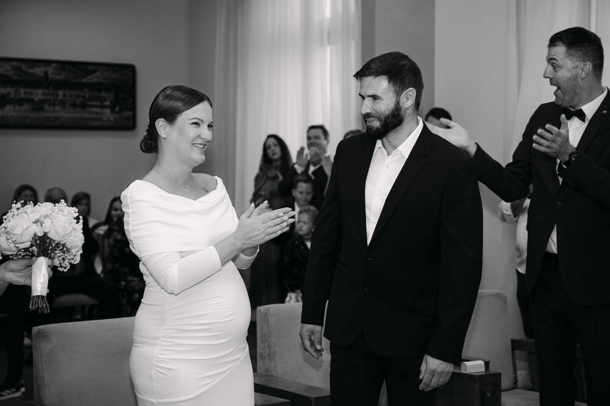 Upravo vjenčani par na svečanosti kod matičara, s prijateljima i obitelji, u elegantnom okruženju.