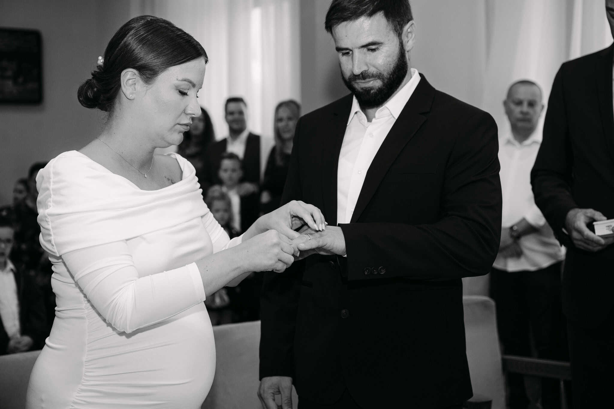 Mladenka i mladoženja na vjenčanju, razmjena prstena u crno-bijelom tonu.