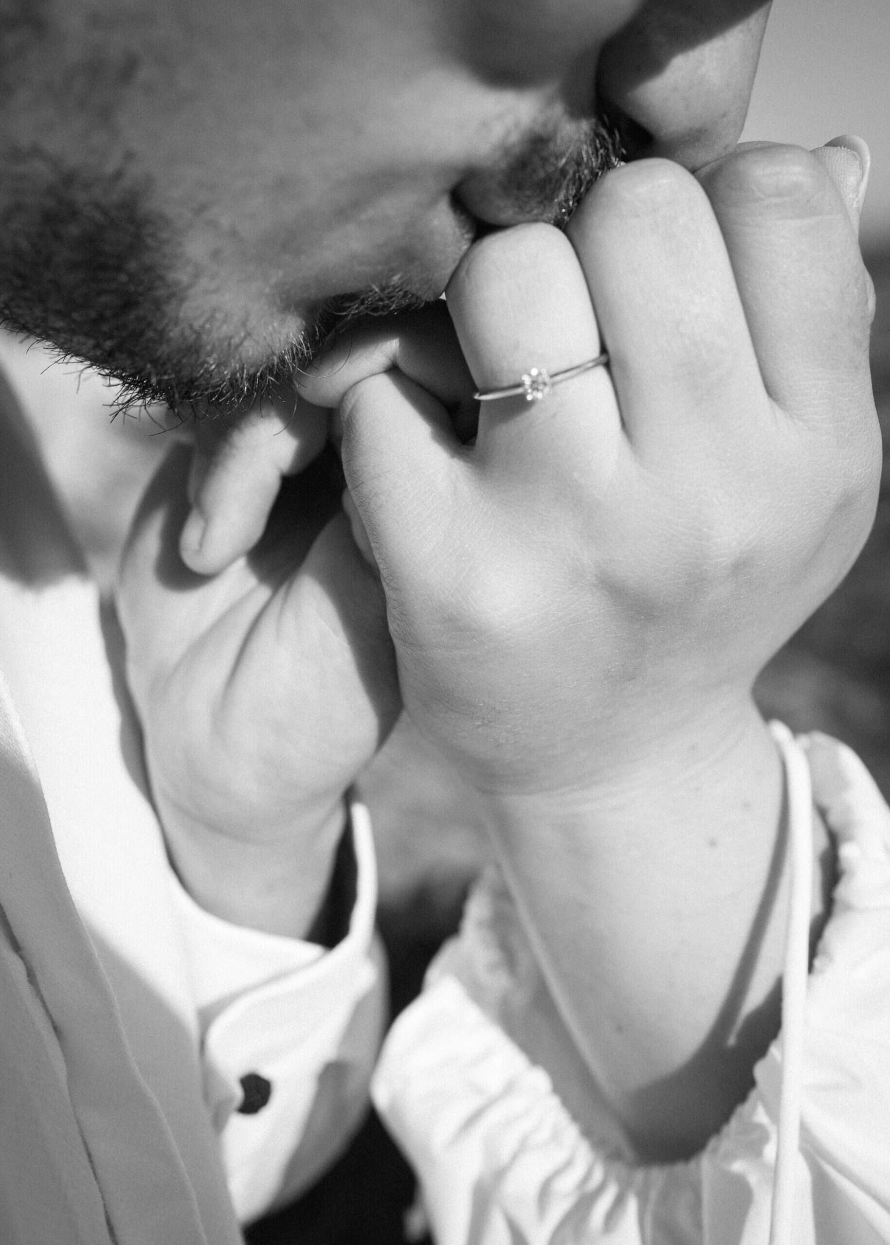 Zaruke u Splitu na otvorenom; crno-bijela fotografija poljupca u ruku s istaknutim dijamantnim prstenom.