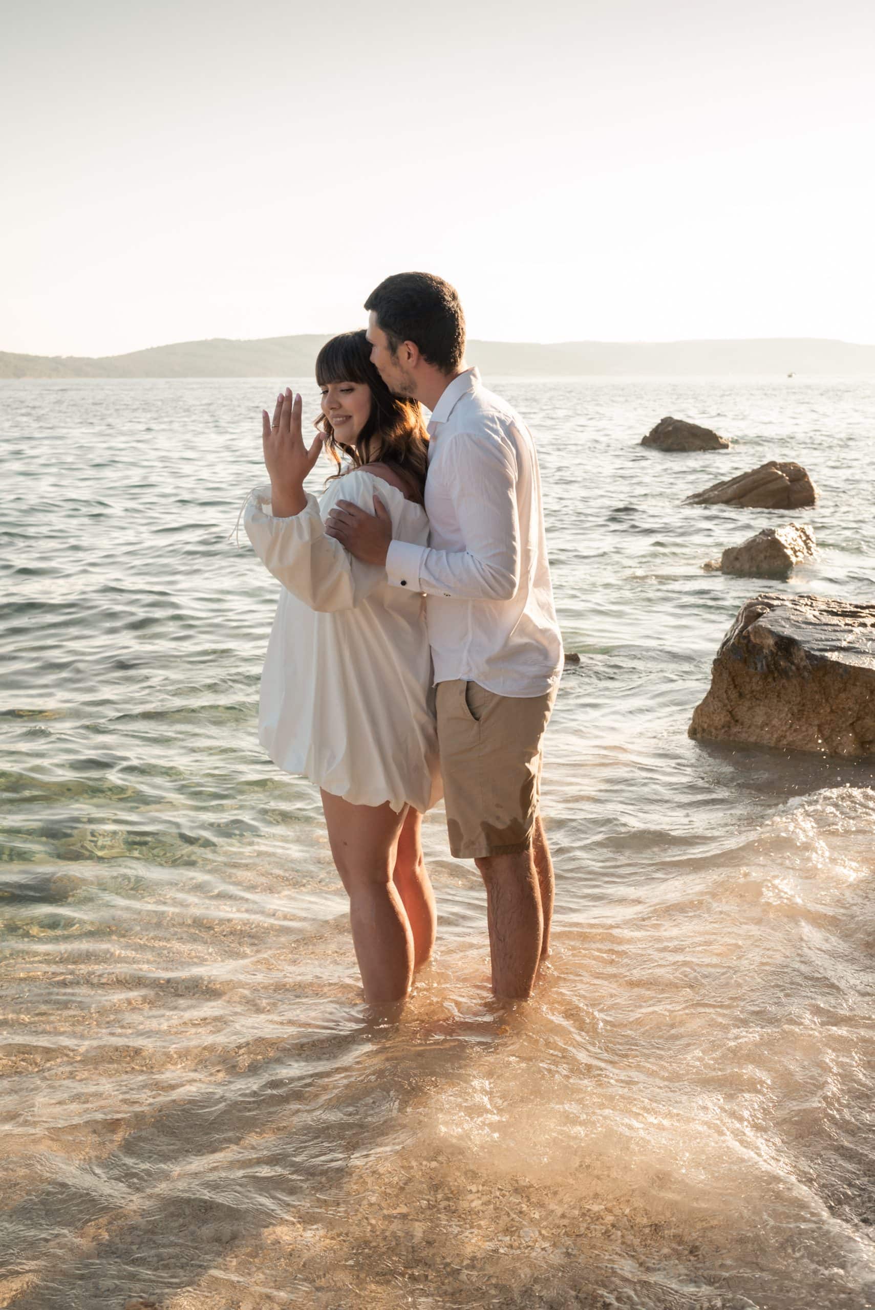 Zaručeni par na plaži Obojena u Splitu, okružen prirodom i morem, uživa u romantičnom trenutku dok stoje u vodi.