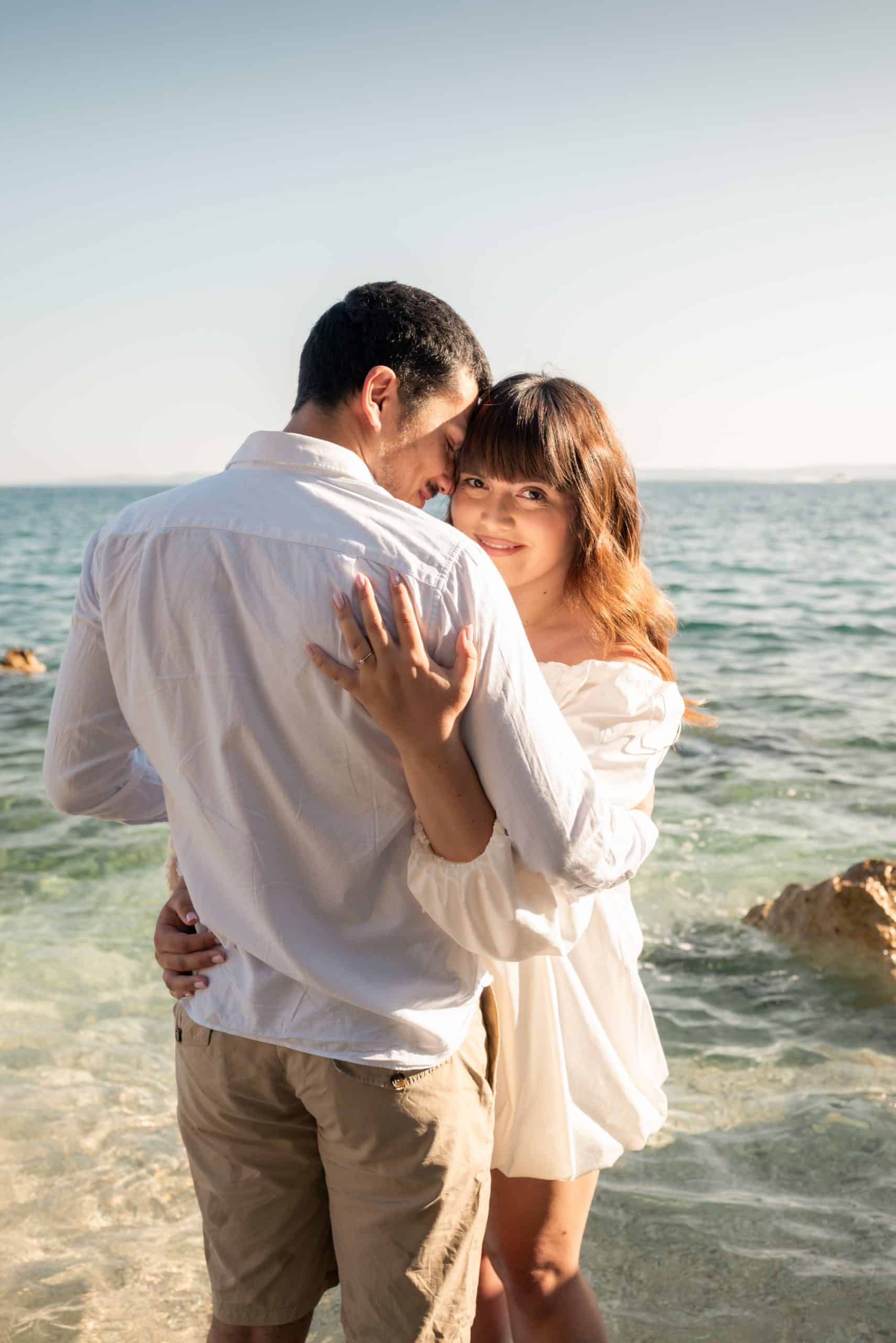 Split Obojena - romantic engagement session; Petra i Ivan zagrljeni u plićaku tijekom zlatnog sata na plaži.