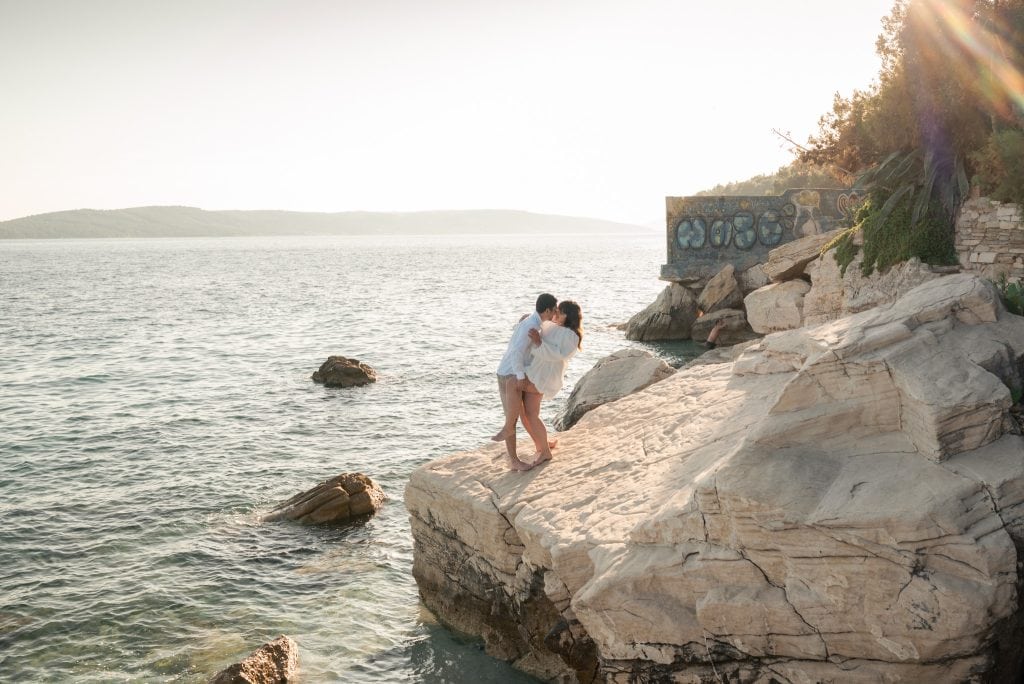 Ljubavni par na stijeni uz more tijekom zalaska sunca.