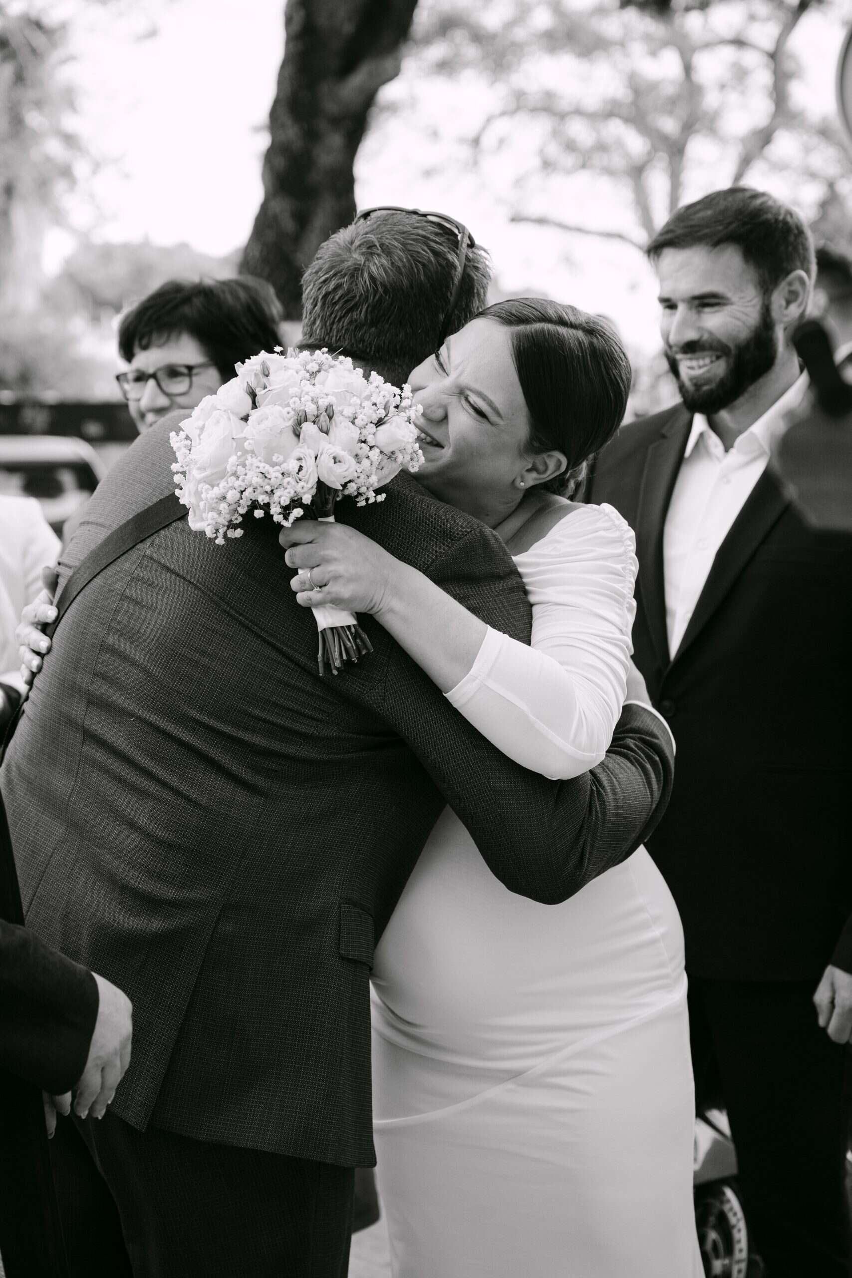 Mladenka i prijatelj u zagrljaju, s osmijehom, prirodna pozadina.