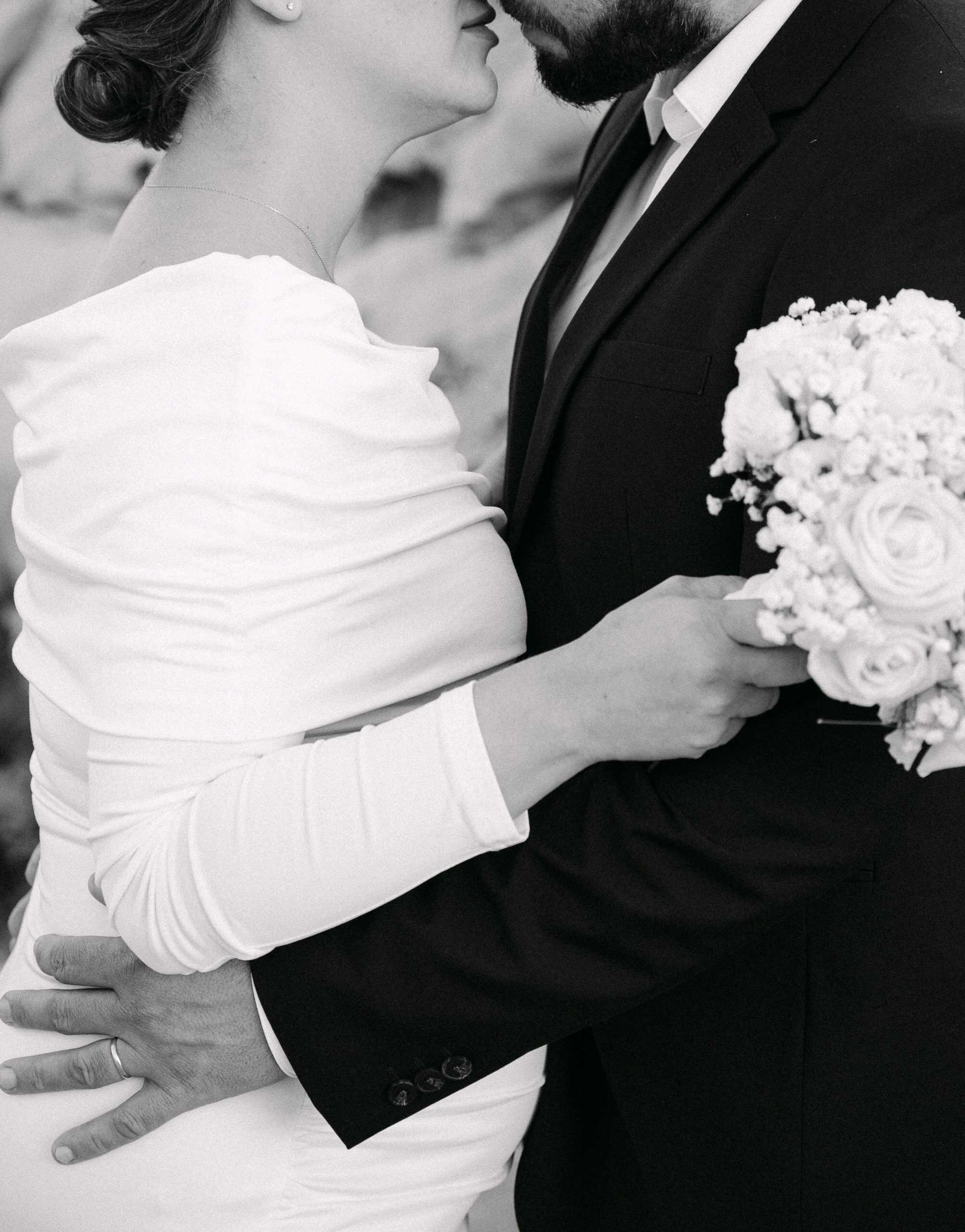 Elegantna crno-bijela vjenčana fotografija para u zagrljaju.