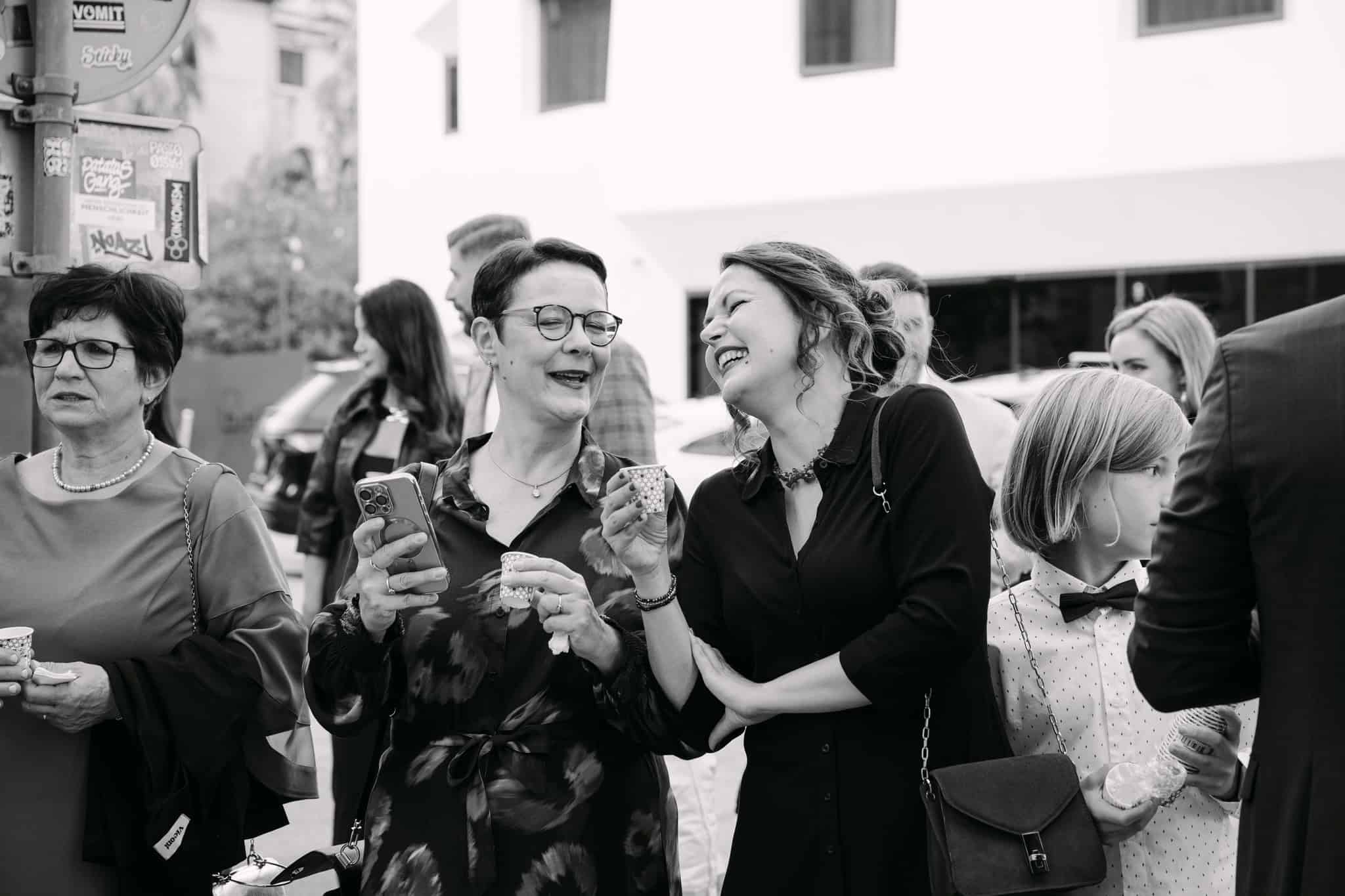 Žene se smiju i pjevaju na vjenčanju u gradu.