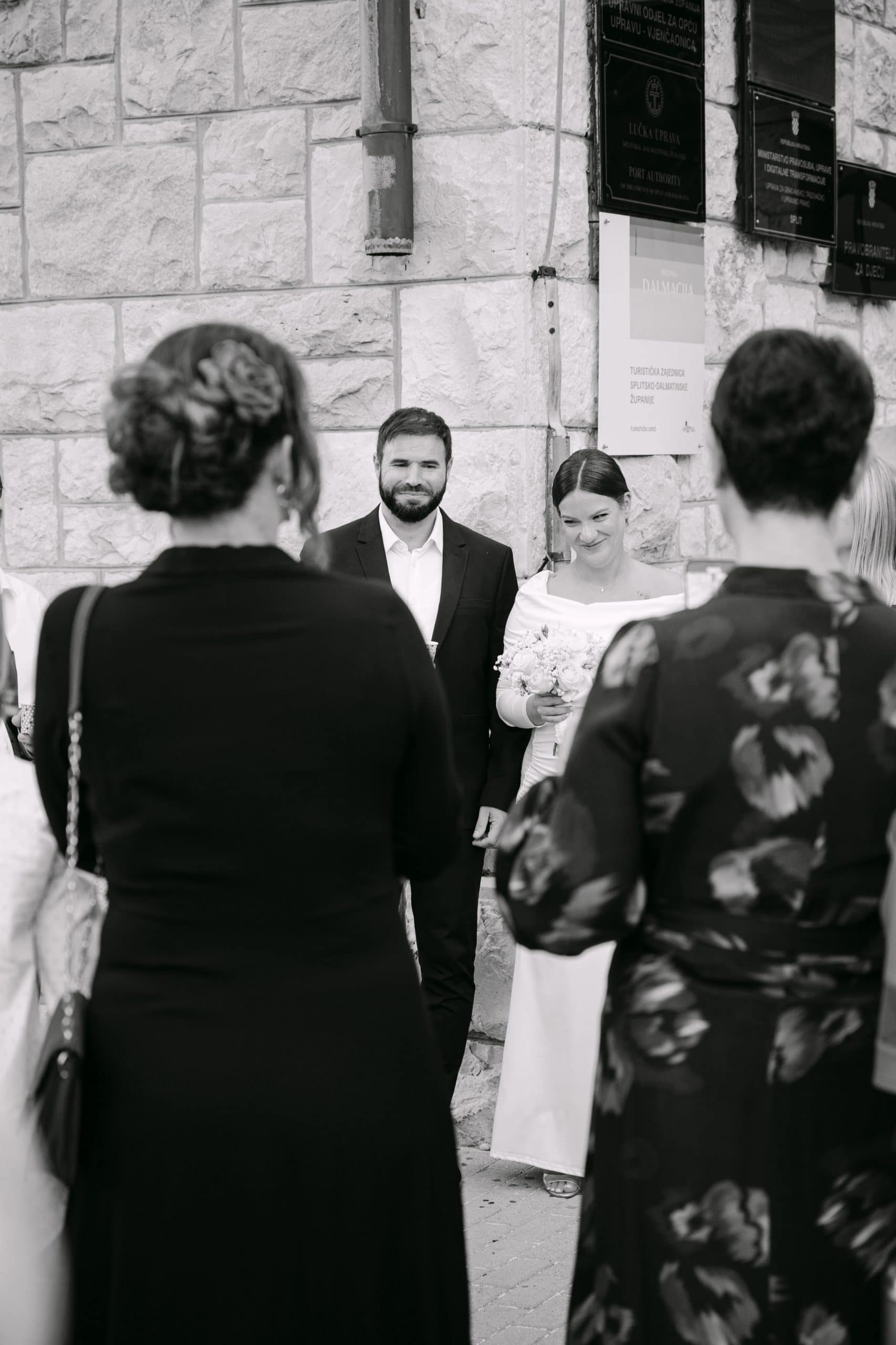 Grupa ljudi ispred matičara, crno-bijela fotografija, spontani trenuci s vjenčanja.
