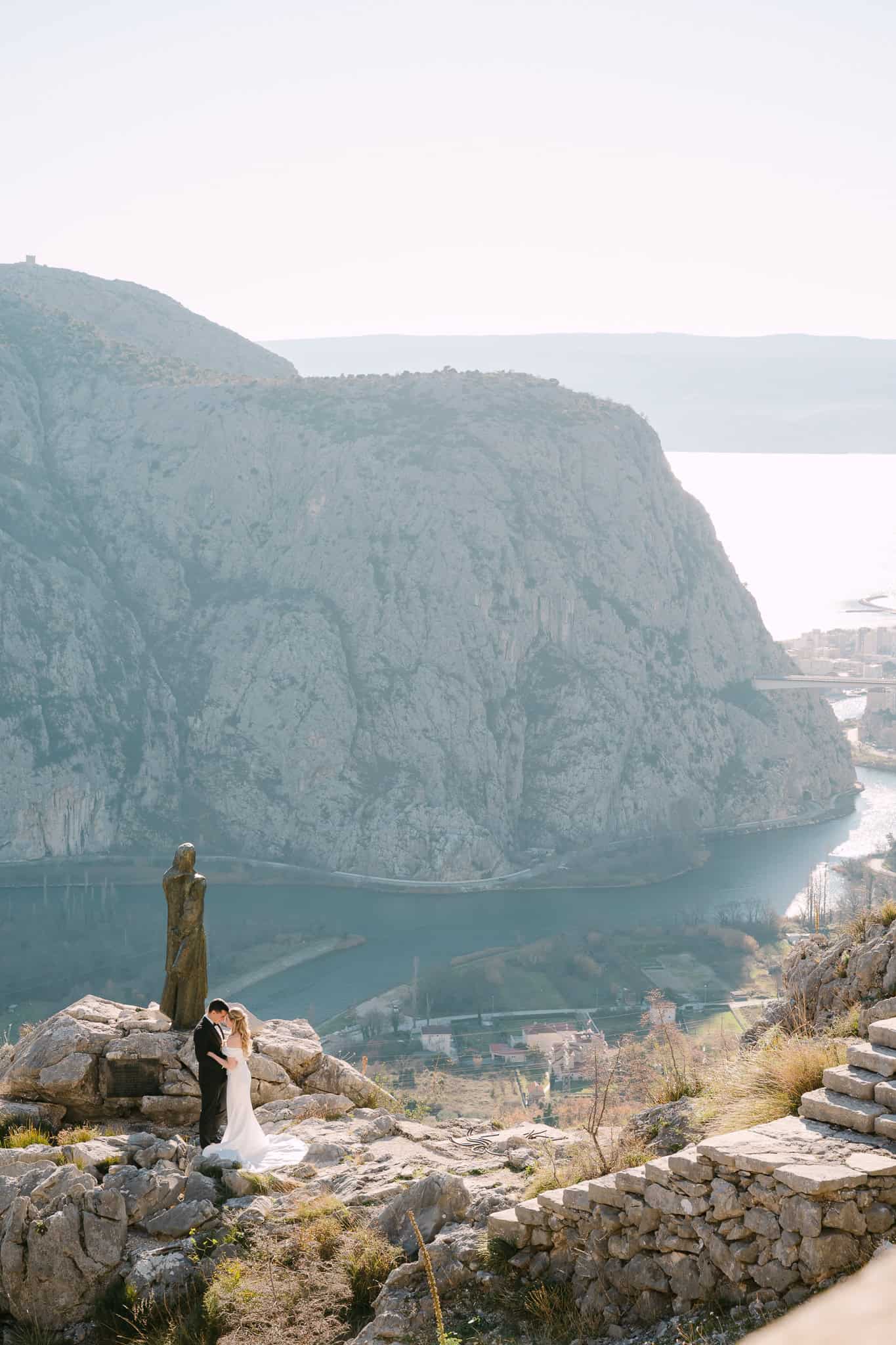 Svadbeni par na kamenom vidikovcu iznad kanjona rijeke Cetine tijekom fotografiranja vjenčanja u Omišu.