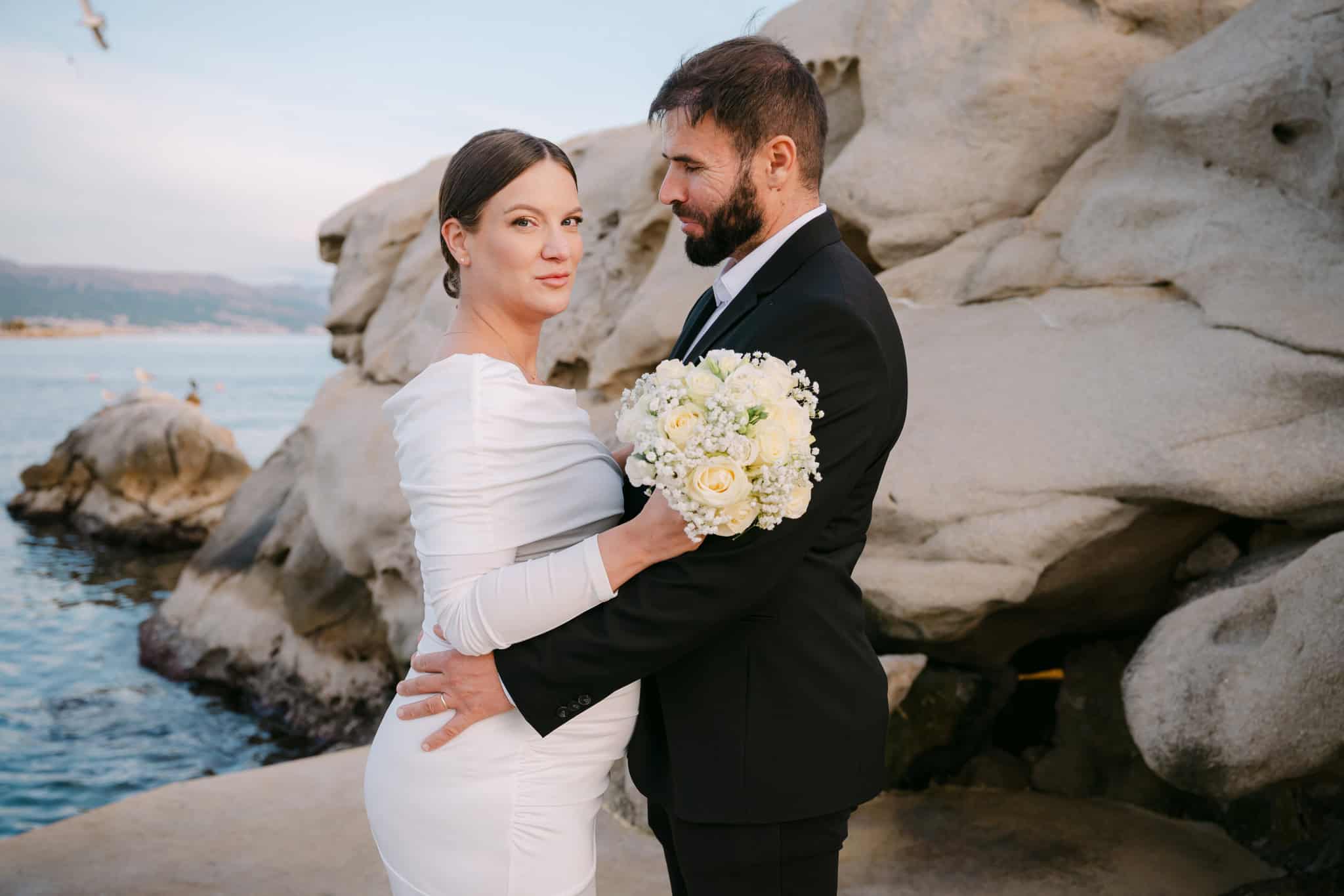 Portret mladenke i mladoženje na stjenovitoj obali grada Splita za vjenčanu fotografiju.