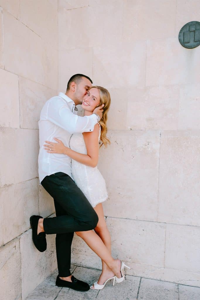 Zaručničko fotografiranje u Splitu na kojem muškarac nasmijano grli djevojku dok stoje ispred svijetlog kamenog zida.