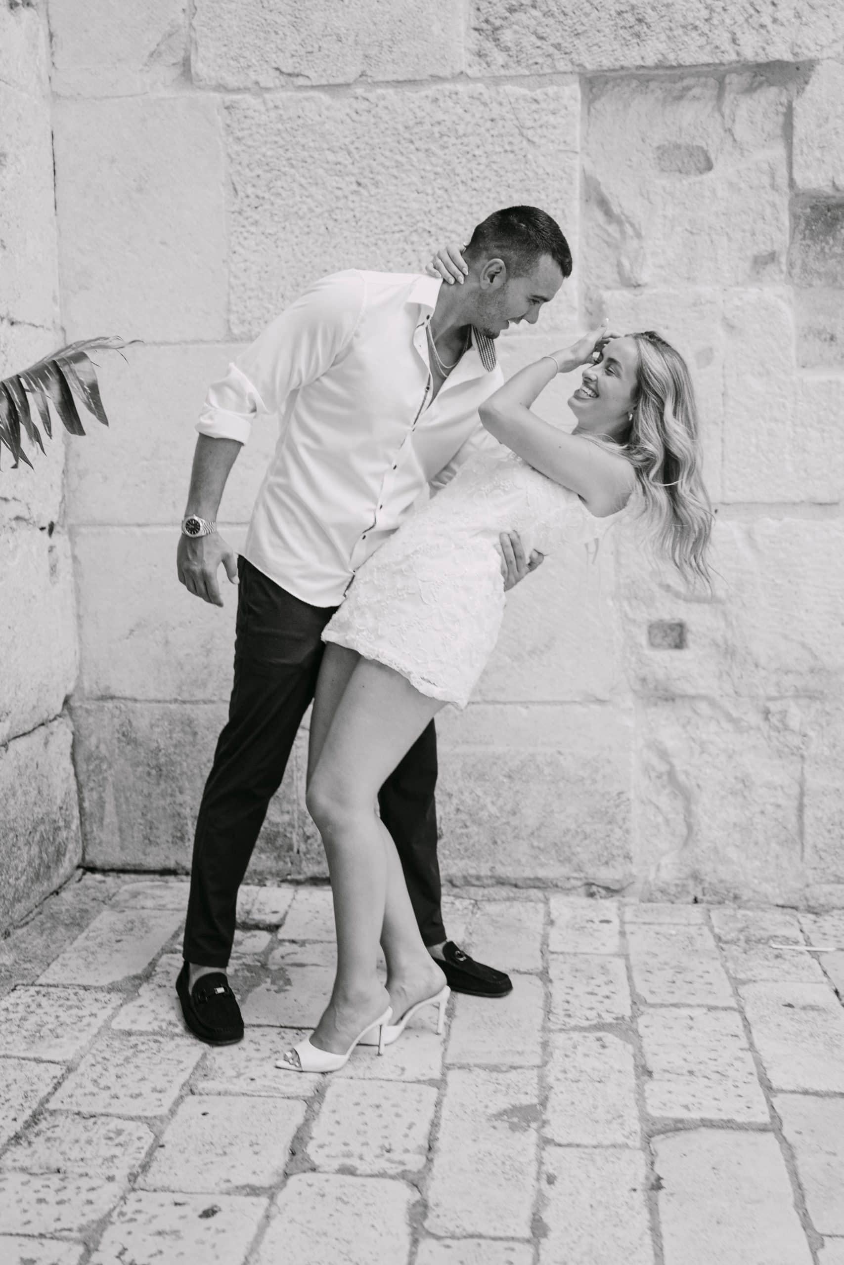 Umjetnički crno-bijeli kadar: zaručnik Ratko drži i spušta Cristinu u romantičan plesni pokret na kamenom trgu u Splitu.