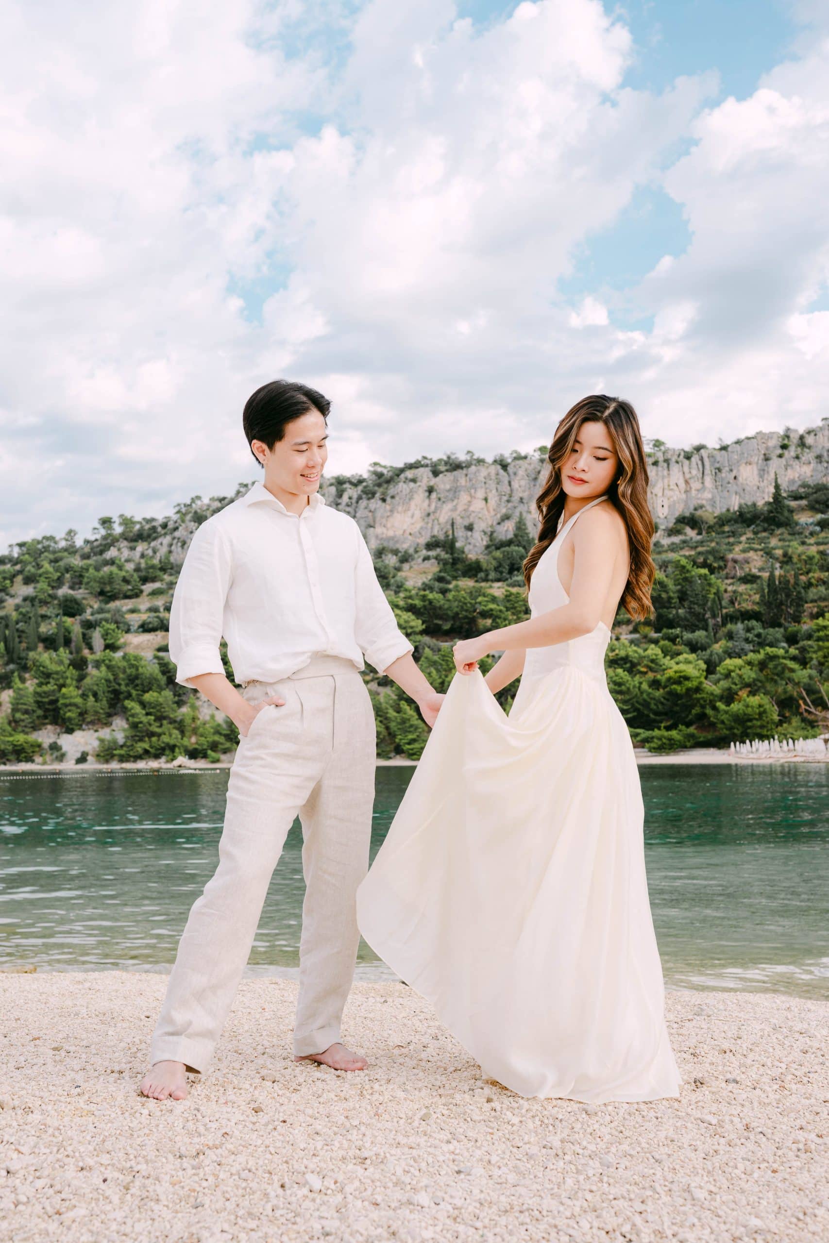 Vjenčani par Stephanie i Bank na plaži Kašjuni u Splitu s impresivnim liticama u pozadini.