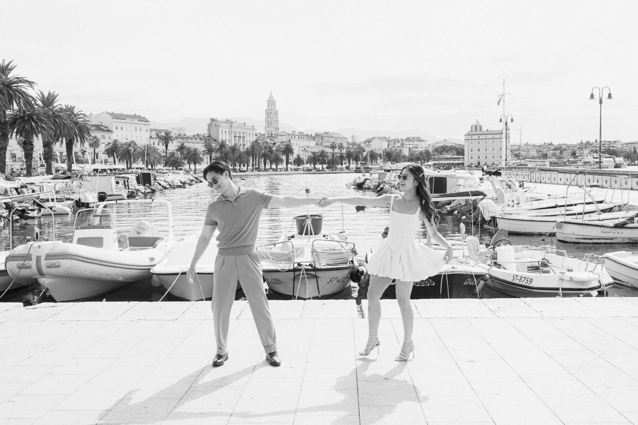 Par pleše na obali grada Splita s brodovima i gradskim pejzažom u pozadini.