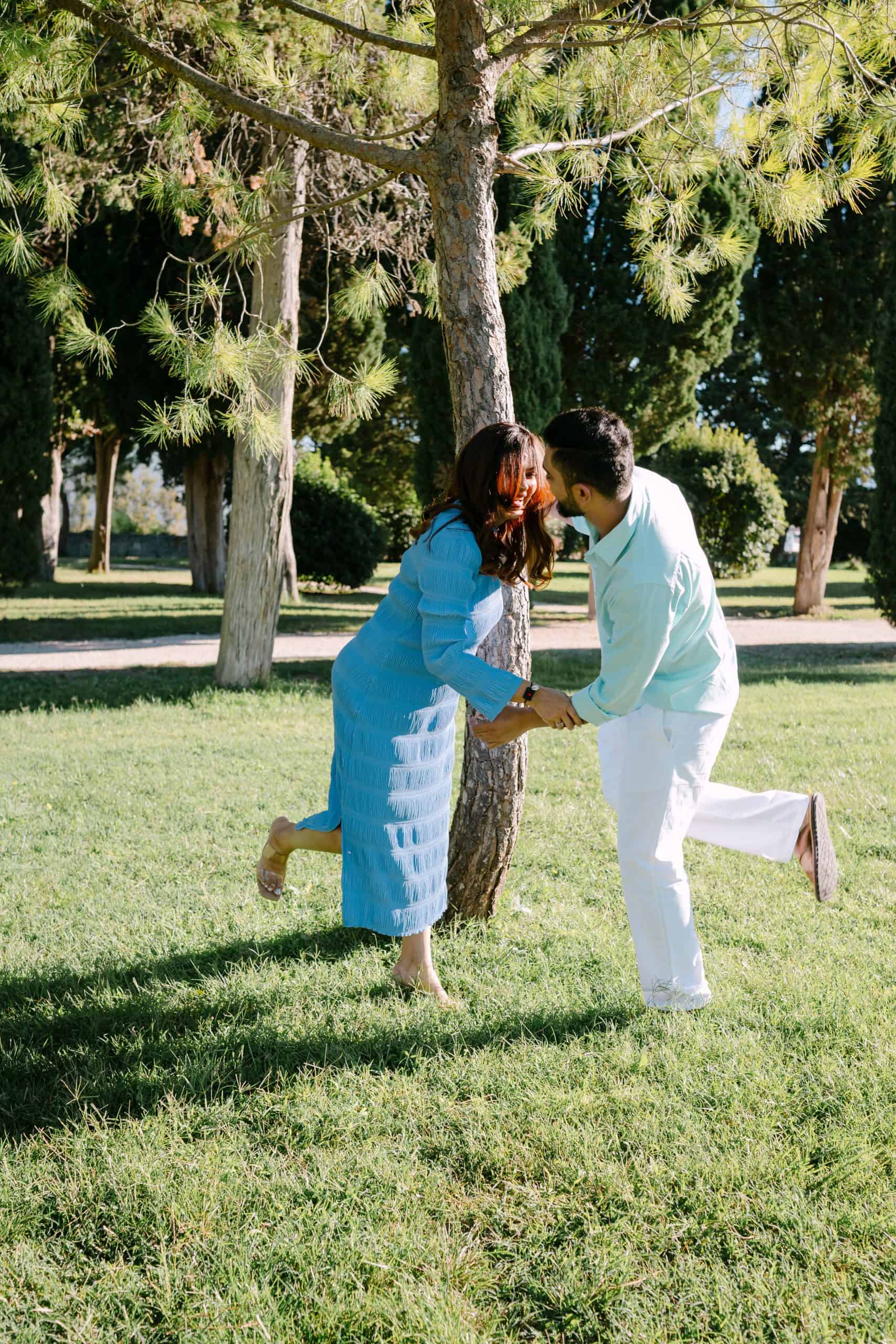 Žena trudnica i suprug koji se hvataju trčeći oko stabla u parku Sustipan.