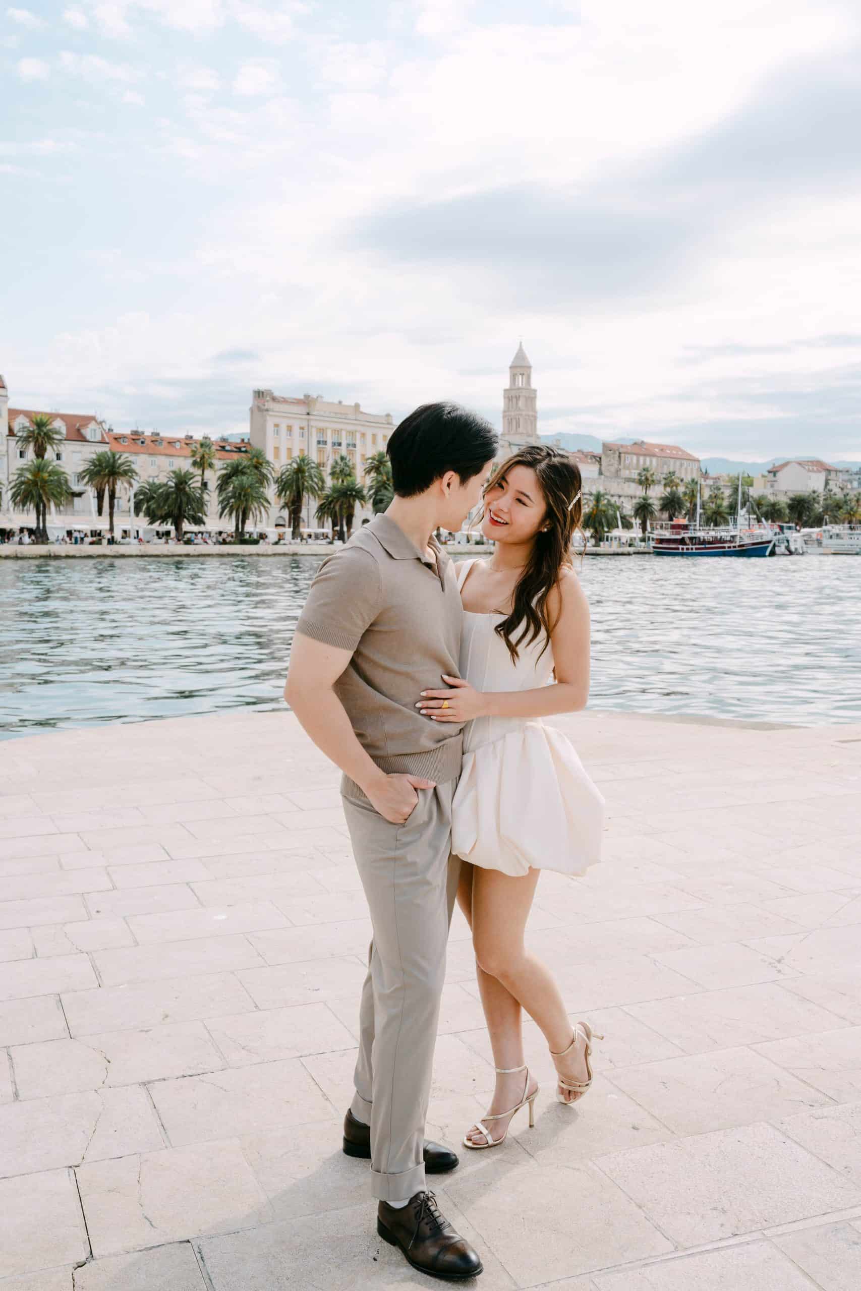 Par se grli uz more s povijesnim gradskim pejzažom i zvonikom Sv. Duje u pozadini.