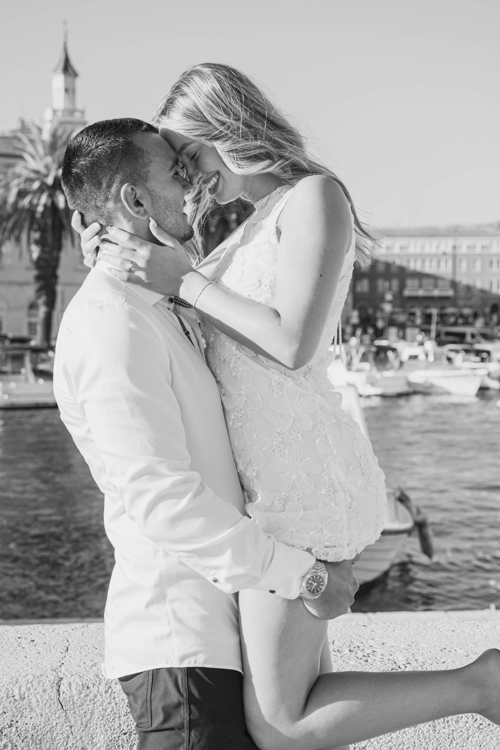 Intiman trenutak zaljubljenog para na rivi, muškarac podiže buduću ženu u zagrljaj.