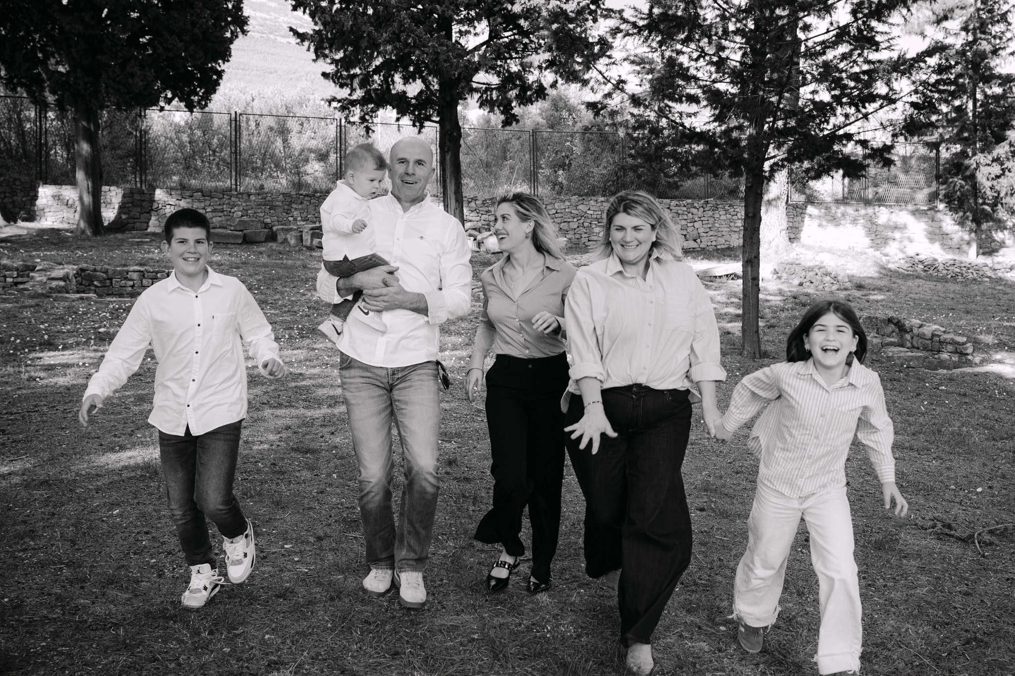 Obitelj šeta zajedno parkom, smiješi se i zabavlja na otvorenom.