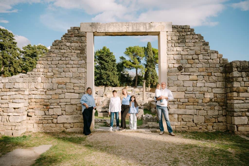 Obitelj ispred drevne kamene ruševine i arheološkog nalazišta.
