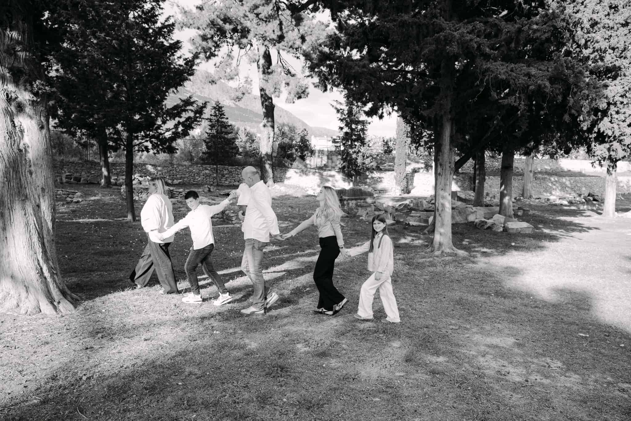 Obitelj se igra i drži se za ruke vani u parku.