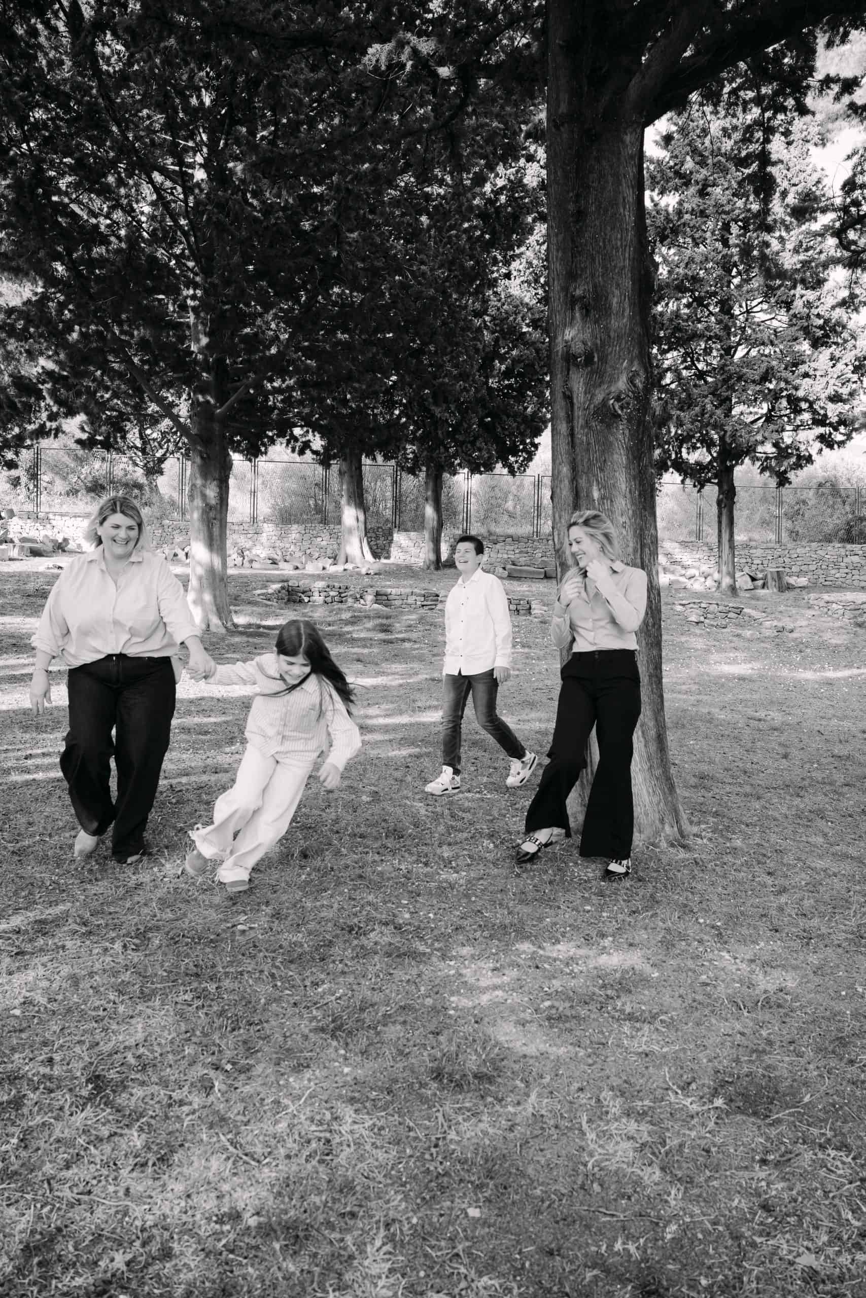 Obiteljska aktivnost na otvorenom u parku s djecom i odraslima pod velikim drvećem.