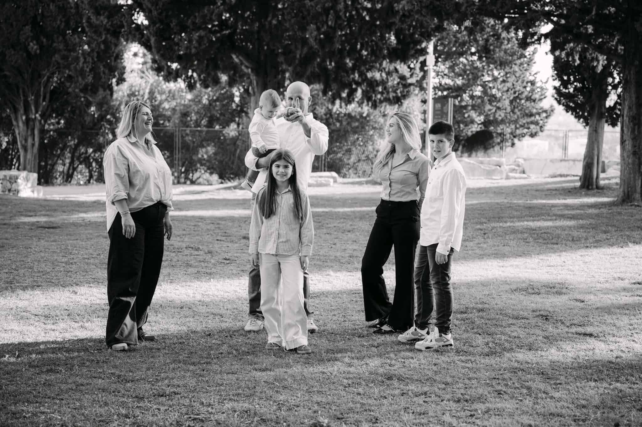 Obiteljska fotografija u parku na otvorenom, iskren trenutak, crno-bijelo, slobodno vrijeme, zajedništvo.