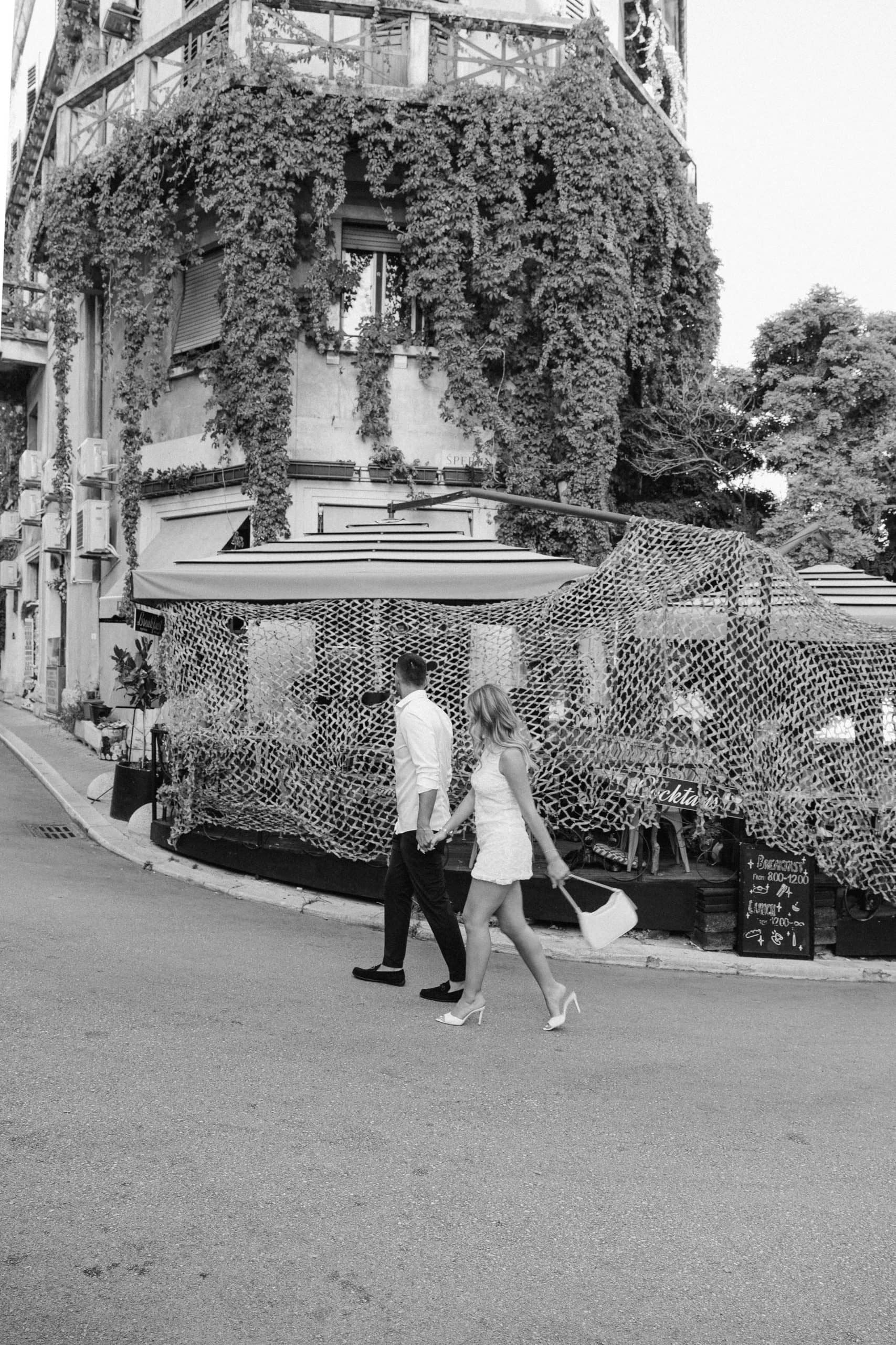 Gradska ulica s zaručenim parom koji prolaze pored zgrade prekrivene bršljanom.