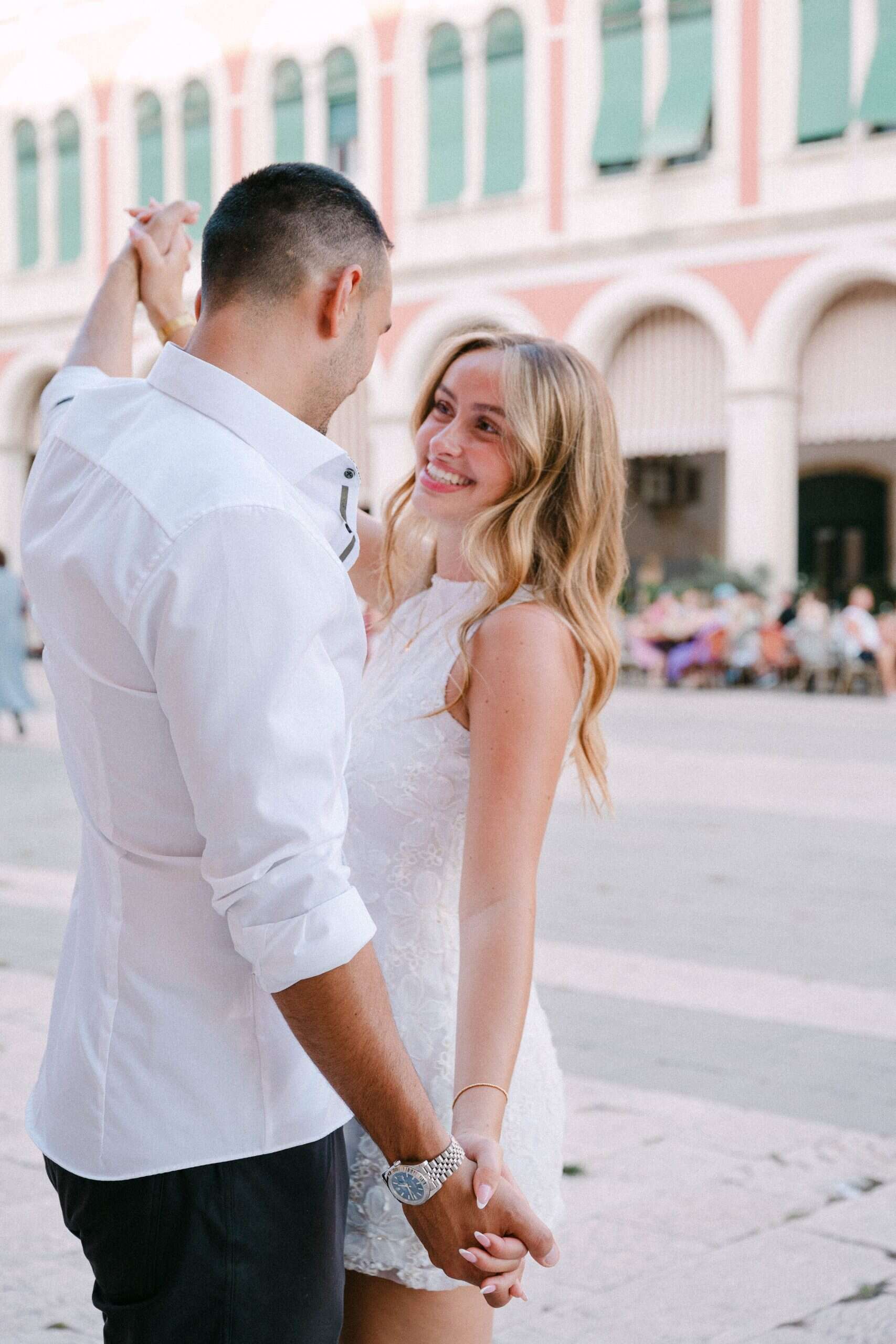 Ljubavni par drži se za ruke i smiješi se u centru grada.