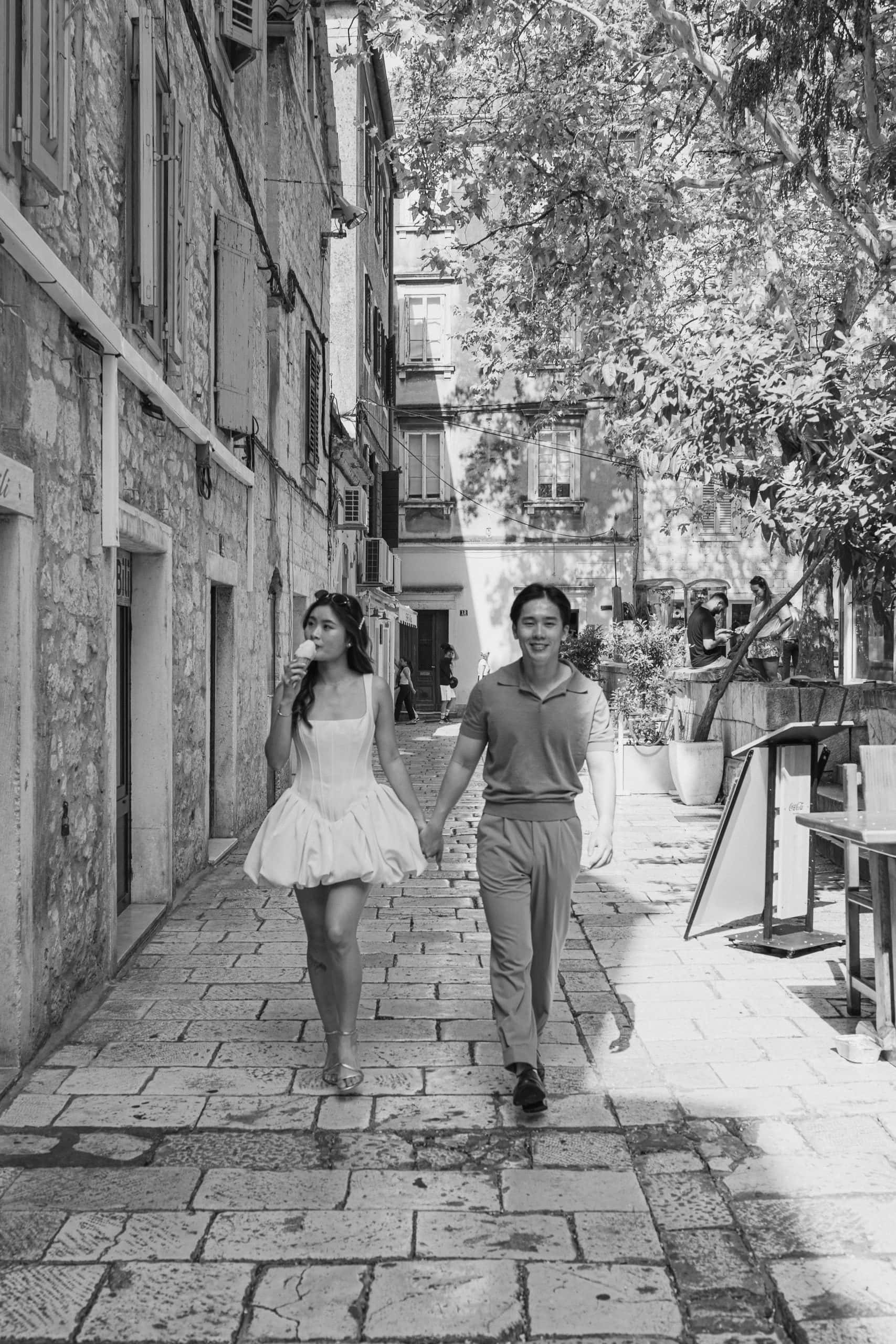 Mladi par šeta povijesnom gradskom ulicom, uživajući u sunčanom danu.