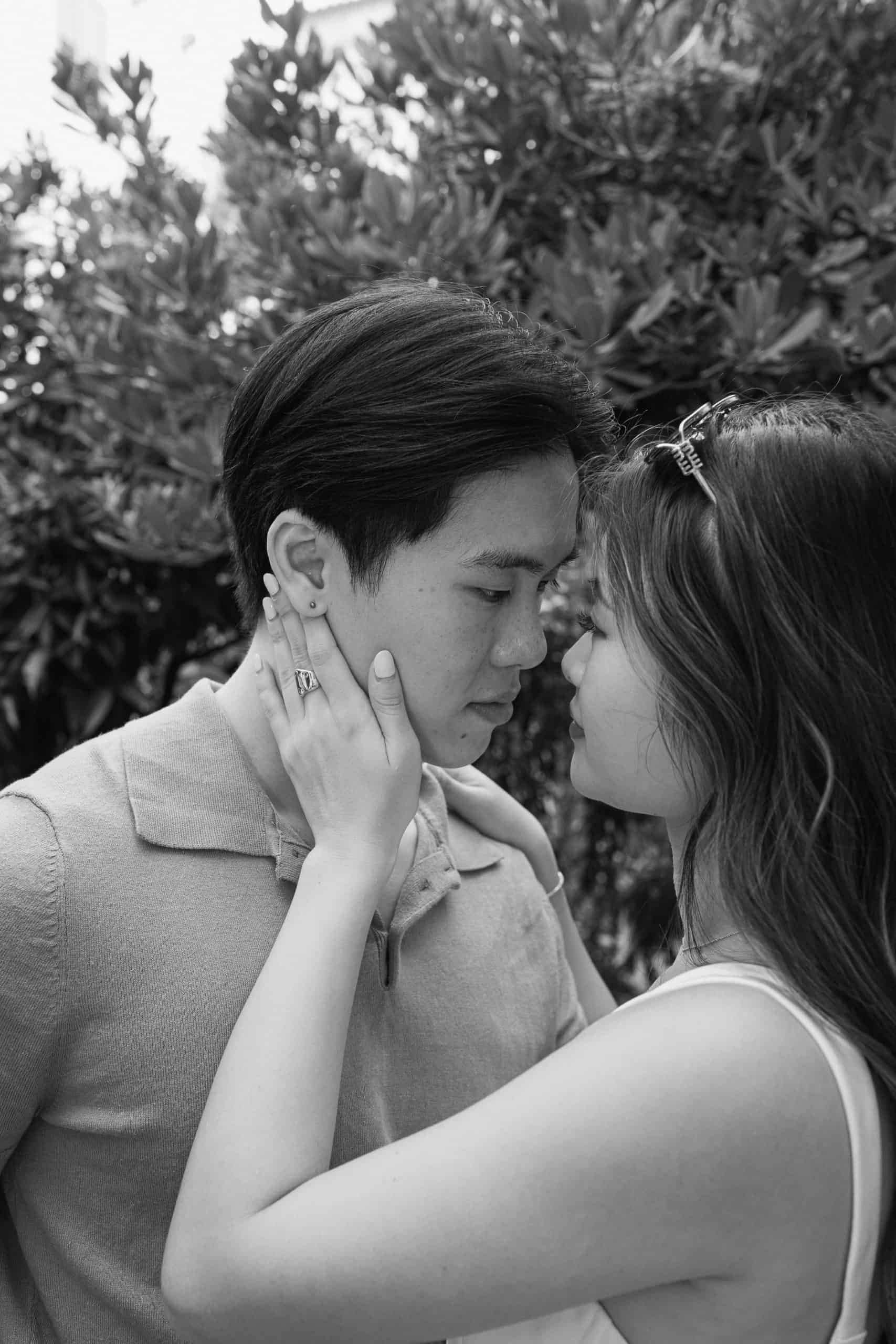 Crno-bijela fotografija zaljubljenog para koji se grli na otvorenom.